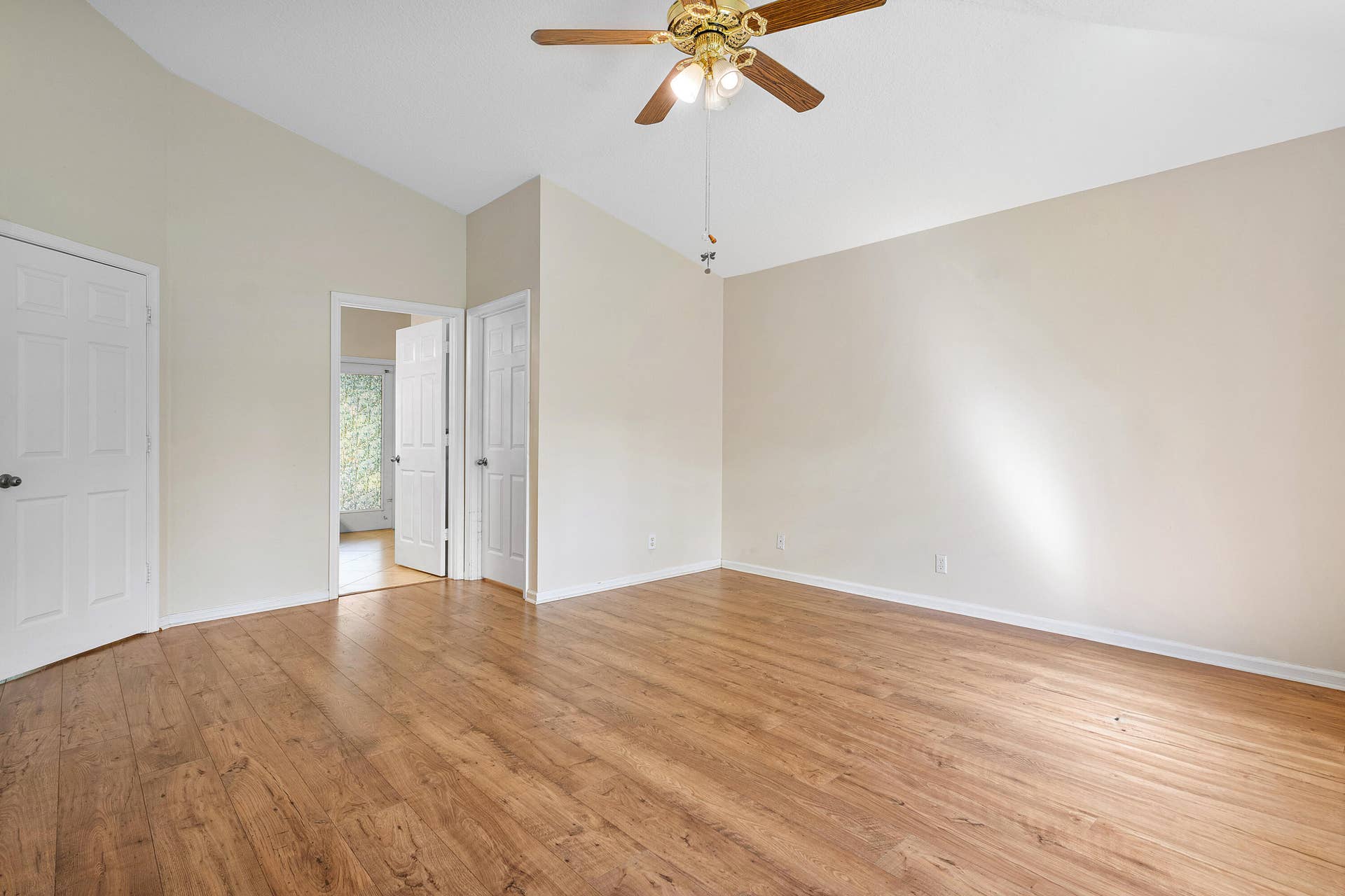 13677 Citrus Grove Boulevard, West Palm Beach, FL 33412 Primary bedroom ensuite number one boasts vaulted ceilings, wood-finish flooring, and a ceiling fan with integrated lighting