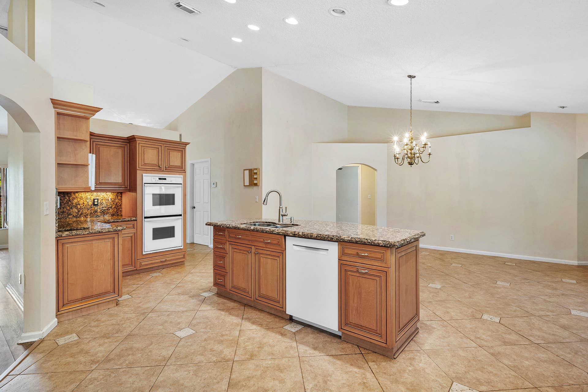 13677 Citrus Grove Boulevard, West Palm Beach, FL 33412 Kitchen featuring raised-panel wood cabinetry, stone countertops, double wall ovens, a center island with integrated dishwasher, and tile flooring throughout