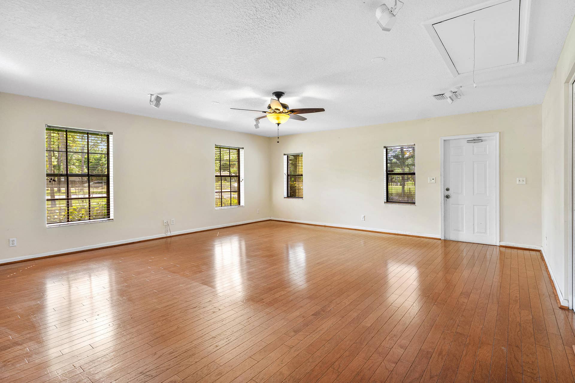 13677 Citrus Grove Boulevard, West Palm Beach, FL 33412 Open interior space featuring wood-finish flooring, recessed lighting, a ceiling fan with integrated light fixture, multiple windows with grid detailing, and a panel door with exterior access