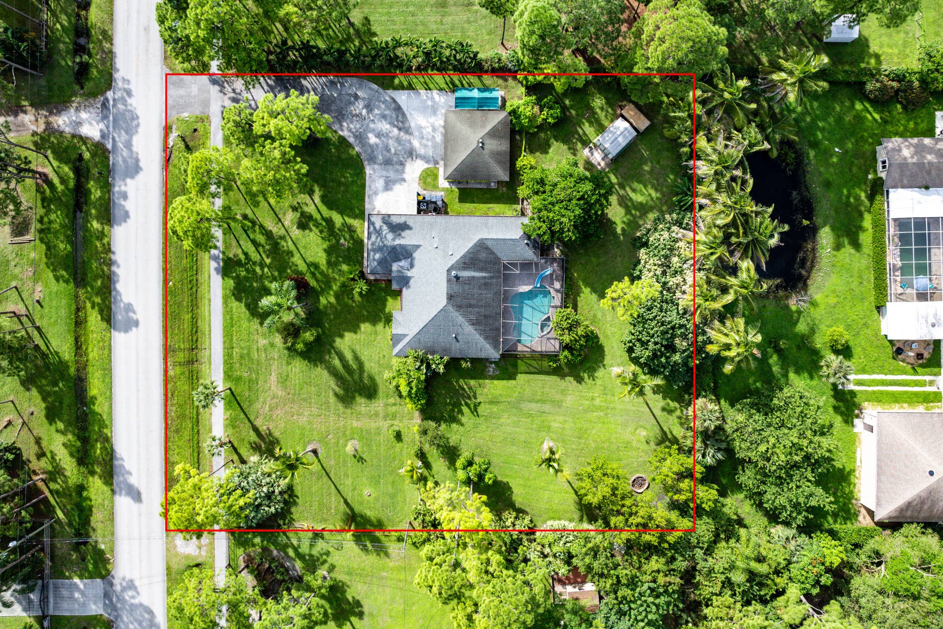 13677 Citrus Grove Boulevard, West Palm Beach, FL 33412 Aerial perspective of a sprawling lot featuring a multi-gabled residence, a screened-in pool, a detached storage structure, and expansive green space with mature landscaping