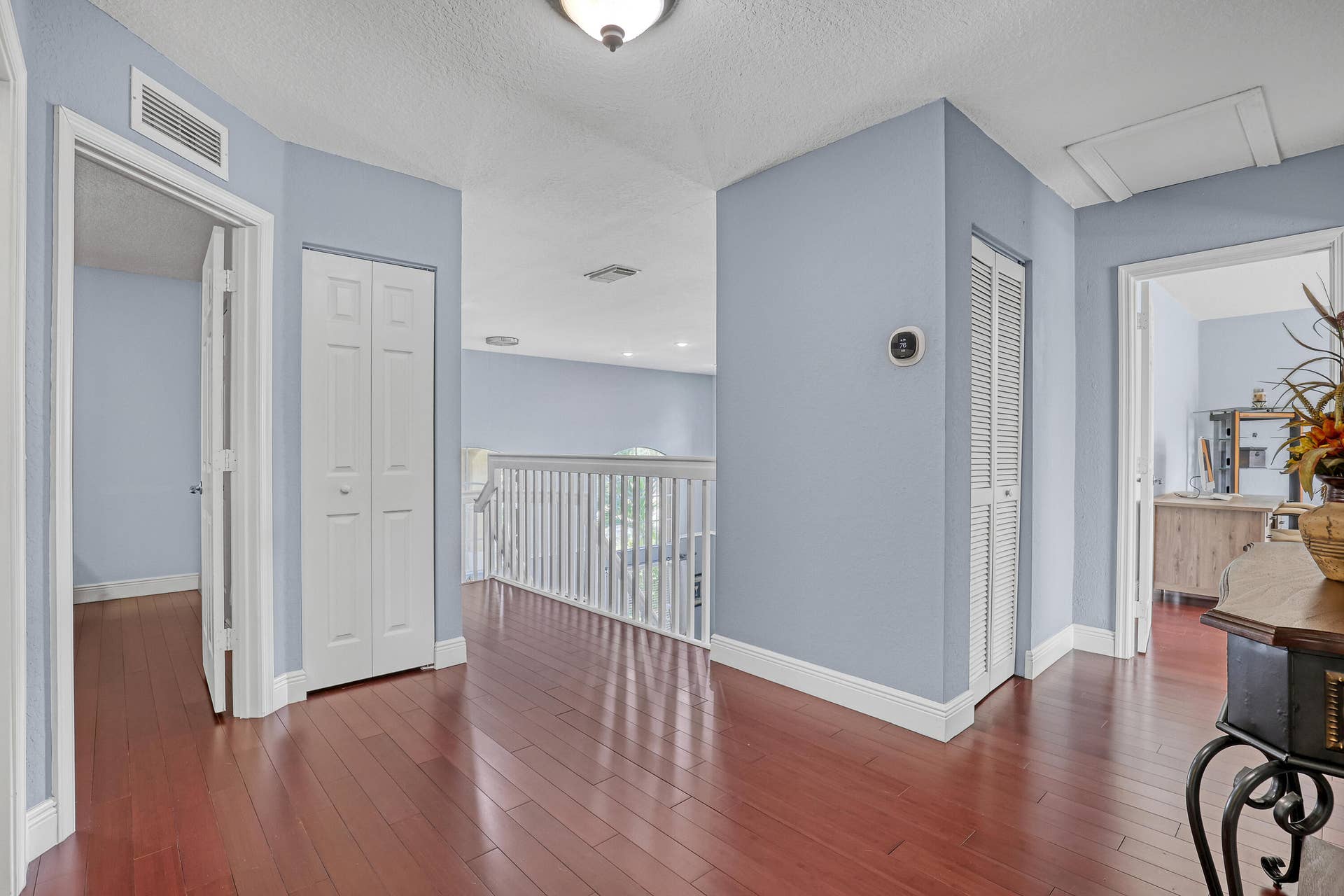 762 GAZETTA Way, West Palm Beach, FL 33413 Wood-finish flooring, white railing with vertical balusters, dual louvered closet doors, and a ceiling-mounted light fixture