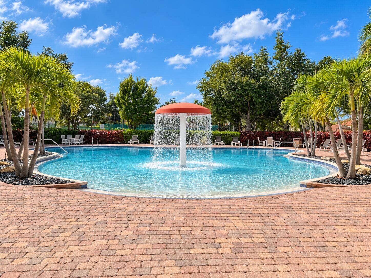 762 GAZETTA Way, West Palm Beach, FL 33413 Swimming pool featuring a zero-entry design, central mushroom water feature, and surround-paver decking accented by palm trees and mature landscaping