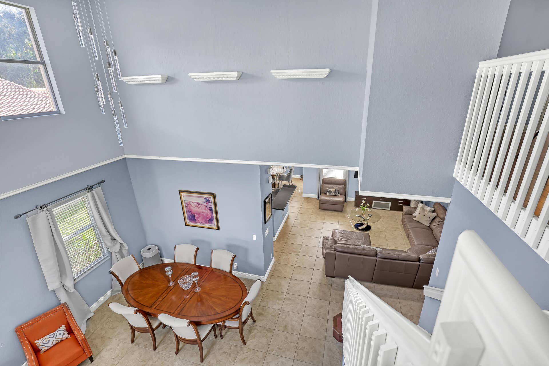 762 GAZETTA Way, West Palm Beach, FL 33413 Double-height ceiling, tile flooring, upper-level landing with white balustrade, wall-mounted decorative ledges, and multi-pane window