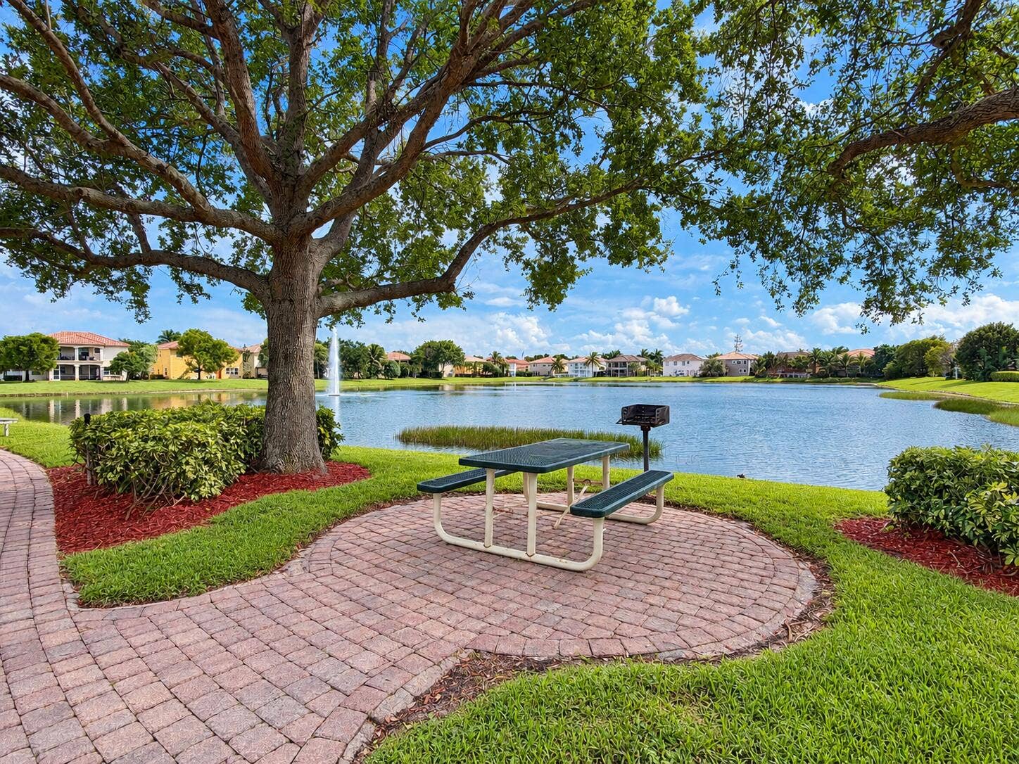 762 GAZETTA Way, West Palm Beach, FL 33413 Waterfront common area featuring a paved brick walkway, mature shade tree, manicured lawn