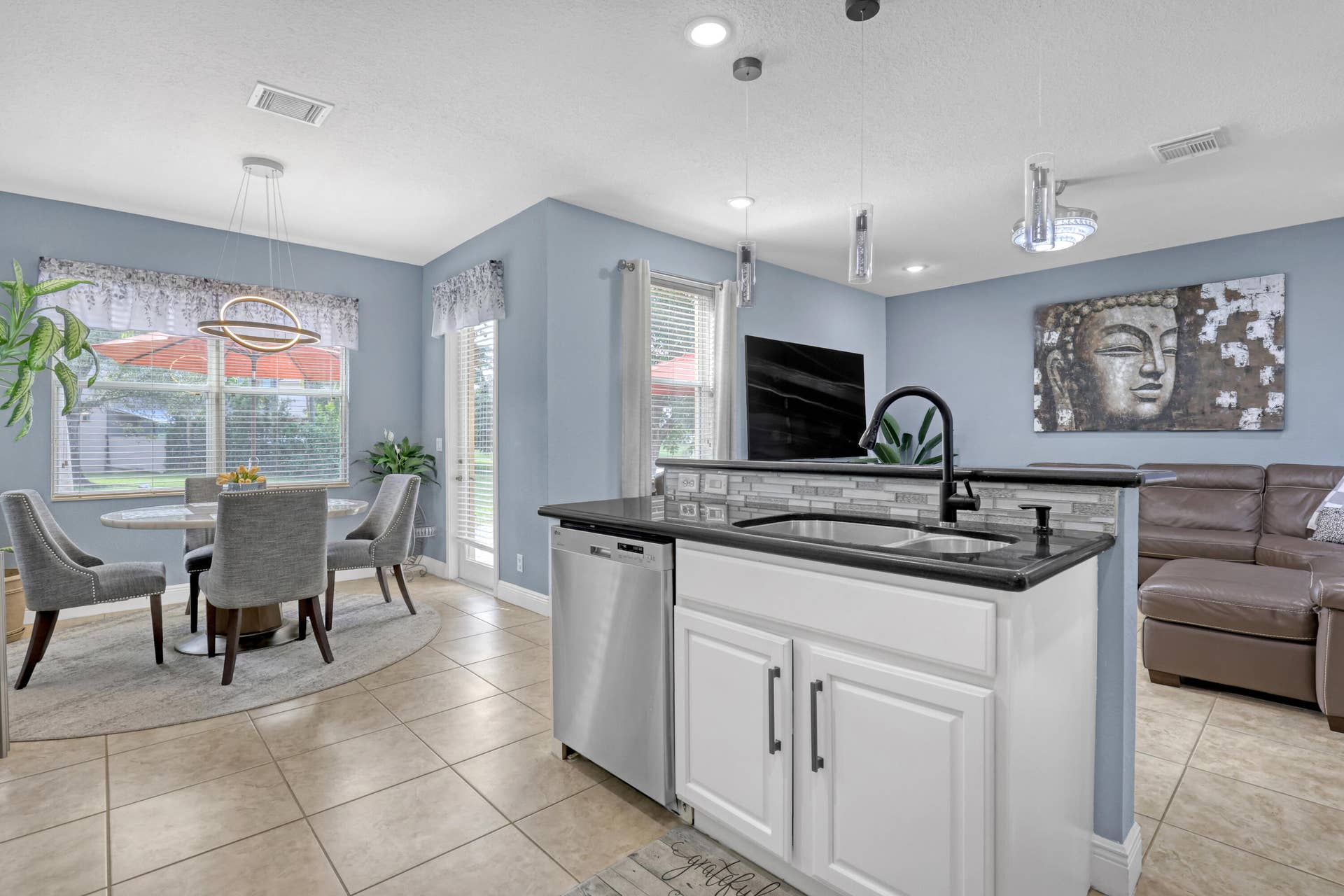 762 GAZETTA Way, West Palm Beach, FL 33413 Kitchen island featuring white cabinetry, a granite countertop, and a matte black faucet, complemented by recessed lighting and neutral tile flooring