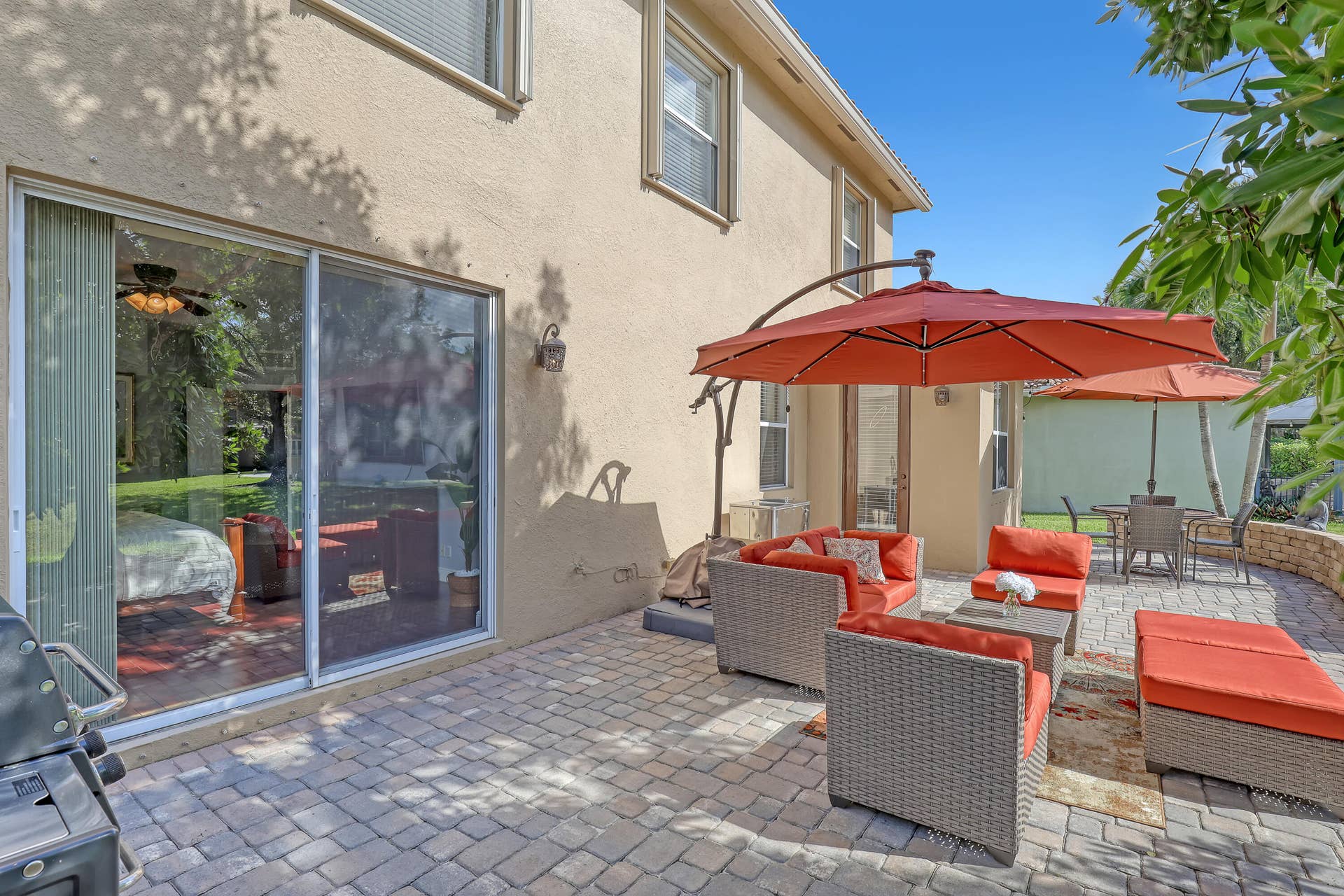 762 GAZETTA Way, West Palm Beach, FL 33413 Stucco exterior featuring a sliding glass door, paved stone patio, and a low-profile stone retaining wall