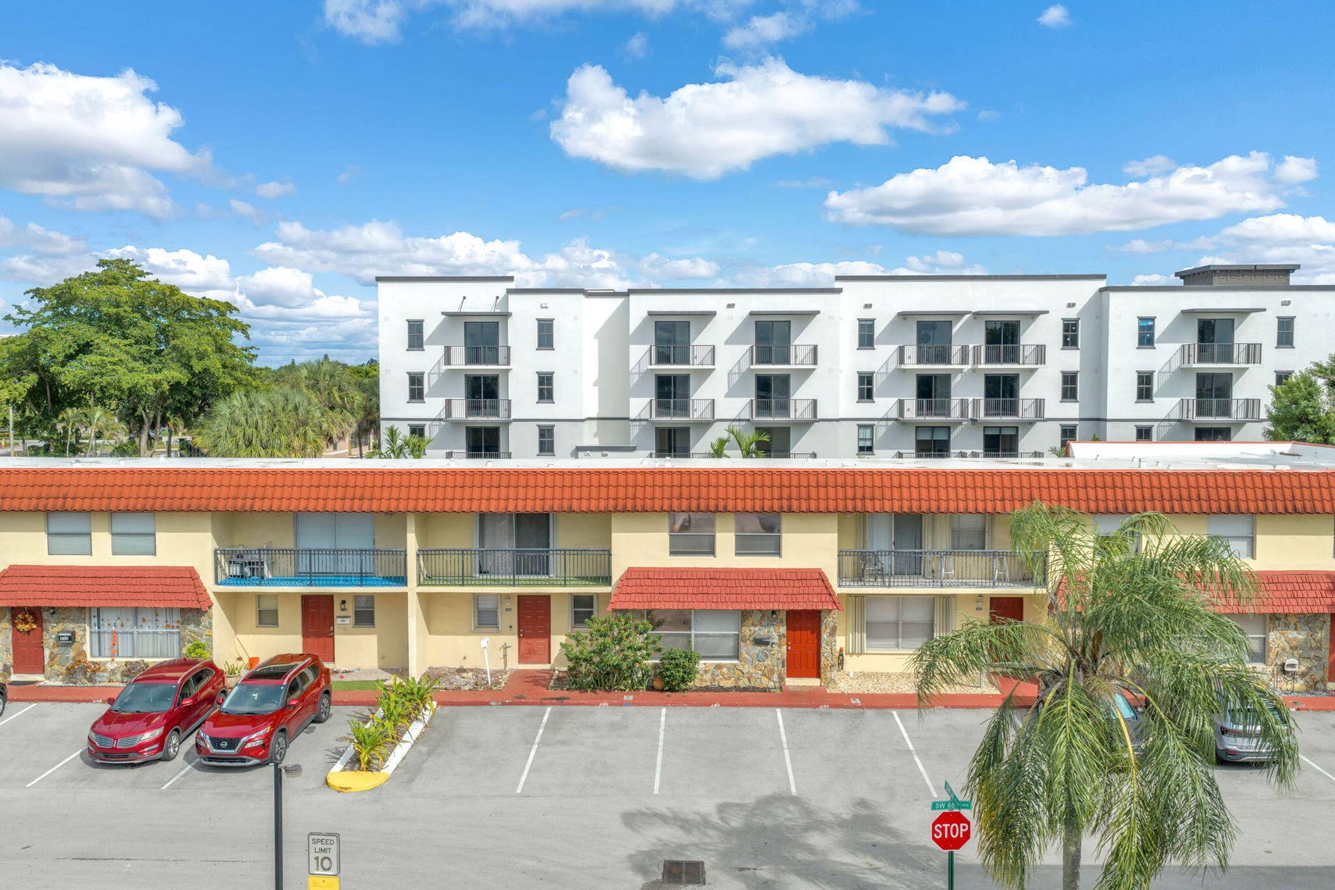 4162 SW 65th Avenue, #84, Davie, FL 33314 Multi-story building exterior featuring a terracotta-style tiled roof, stone-veneer accent walls, and private balconies with metal railings
