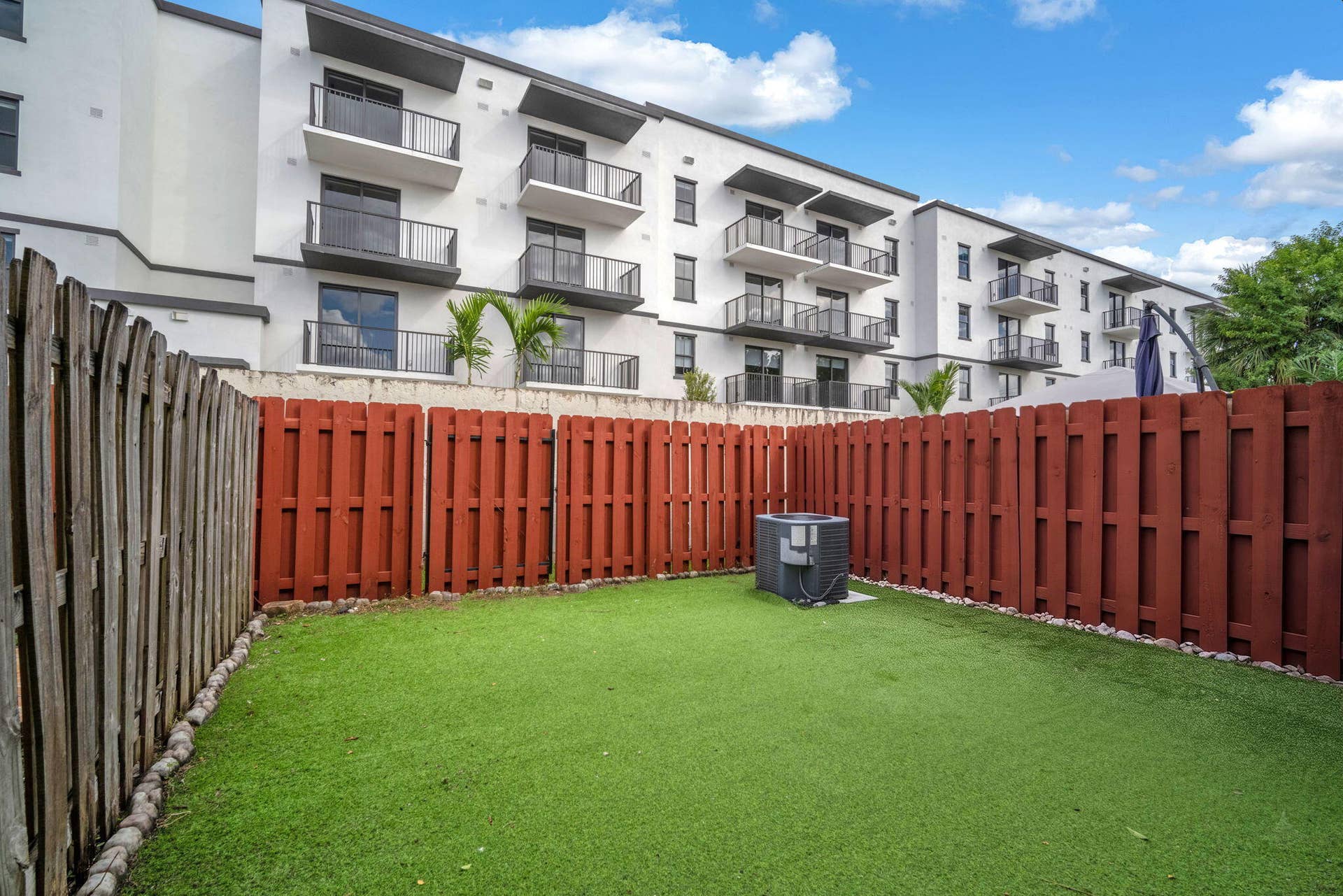 4162 SW 65th Avenue, #84, Davie, FL 33314 Private fenced yard featuring synthetic turf and a multi-story exterior facade with tiered balconies
