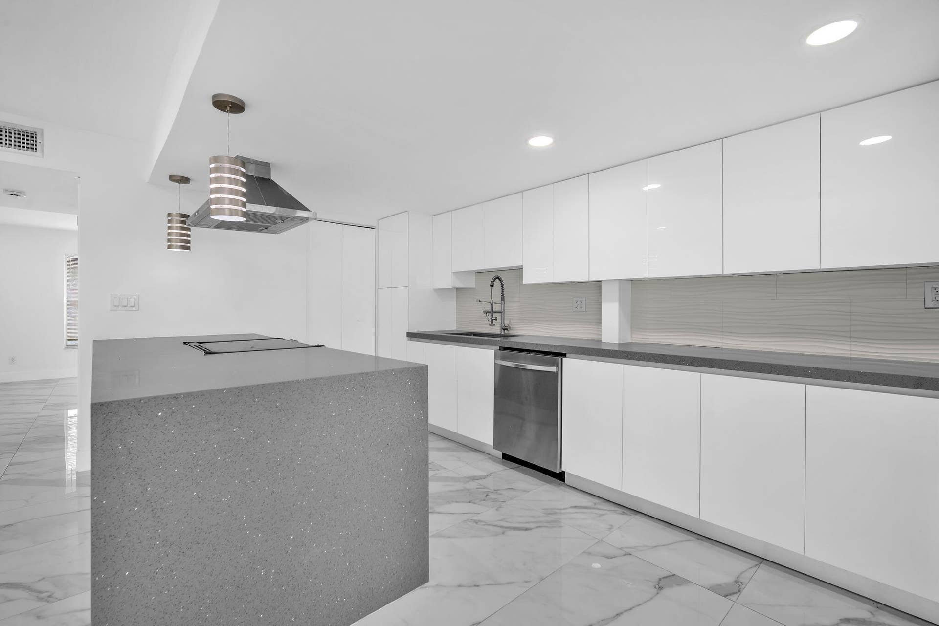 4162 SW 65th Avenue, #84, Davie, FL 33314 Modern kitchen featuring high-gloss white cabinetry, a large central island with a solid-surface countertop, recessed ceiling lighting, stainless steel appliances, and large-format tile flooring