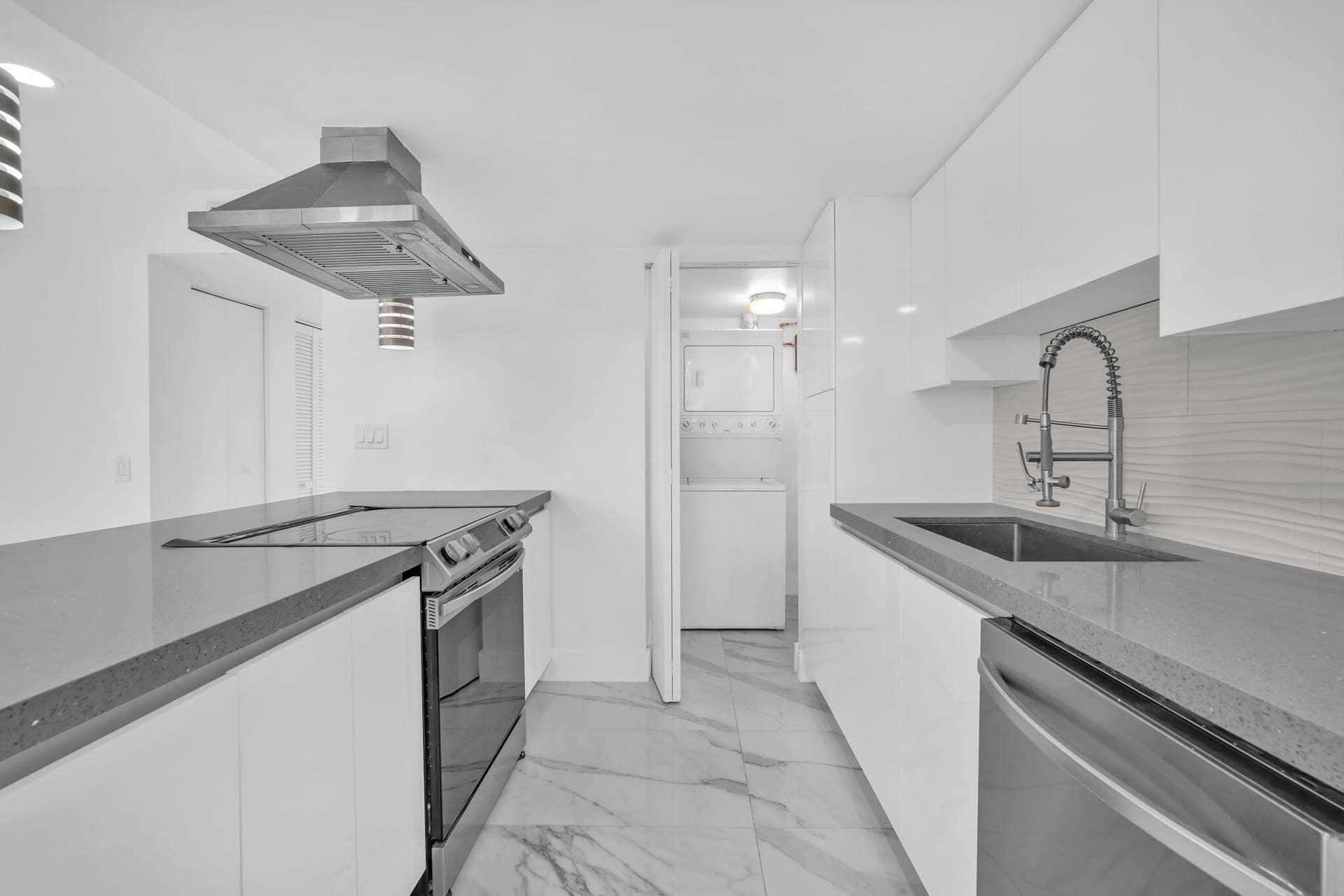 4162 SW 65th Avenue, #84, Davie, FL 33314 Modern kitchen featuring high-gloss white cabinetry, solid-surface countertops, stone-patterned tile flooring, a stainless steel range hood, and a high-arc pull-down kitchen faucet