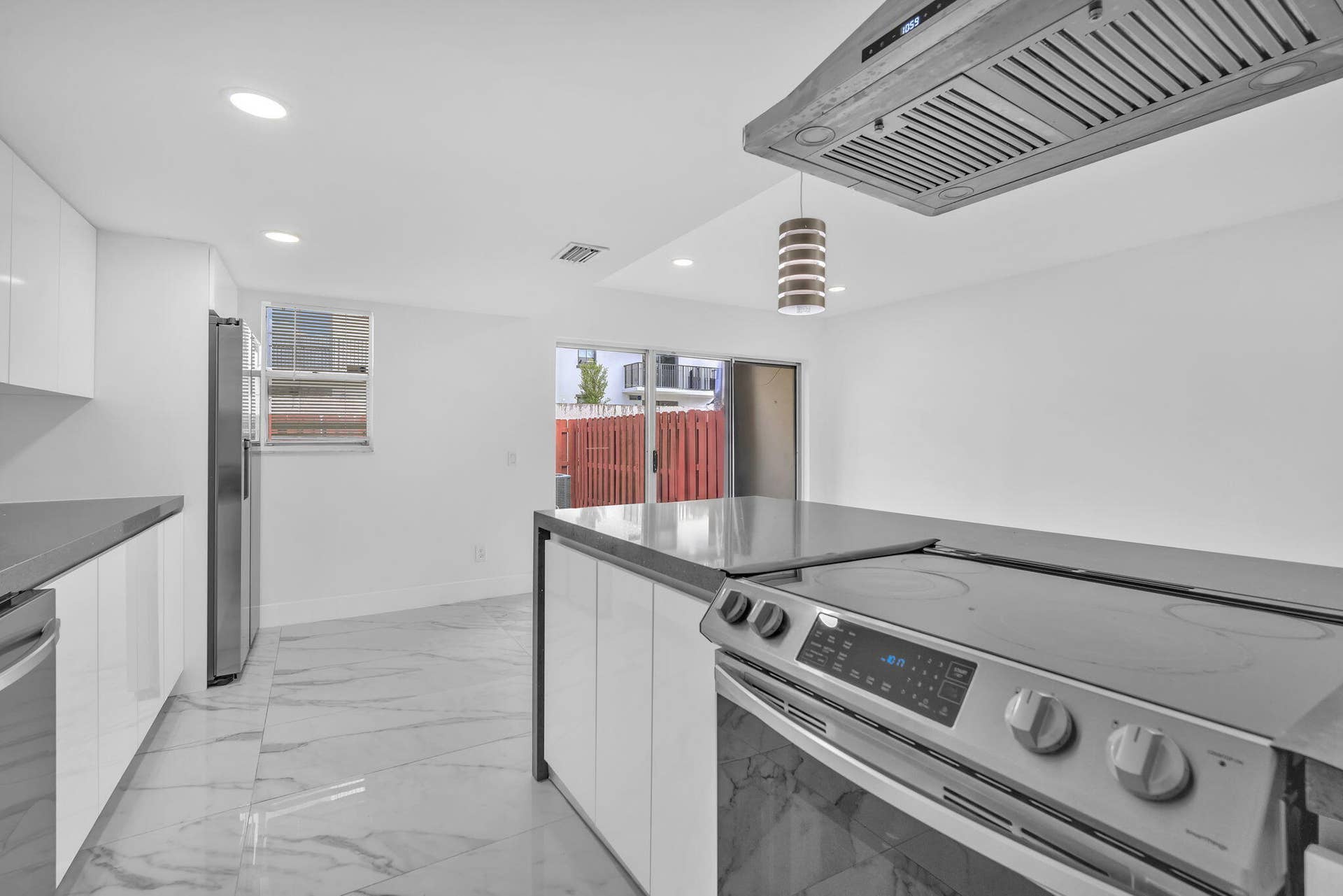 4162 SW 65th Avenue, #84, Davie, FL 33314 Kitchen featuring high-gloss cabinetry, stone-finish countertops, stainless steel appliances, a ceiling-mounted range hood, and large-format porcelain tile flooring
