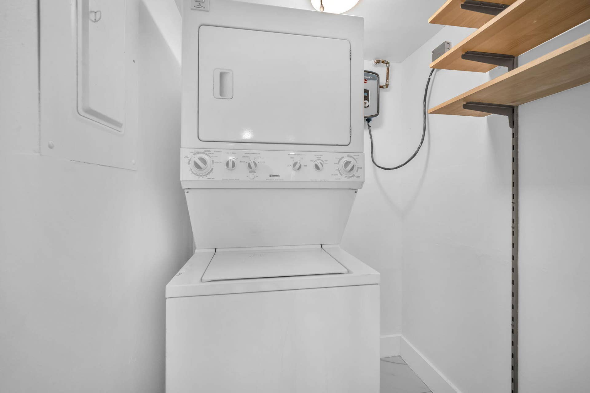 4162 SW 65th Avenue, #84, Davie, FL 33314 Stacked laundry unit featuring a top-loading washer, dryer, built-in wall shelving, and an tankless electric water heater
