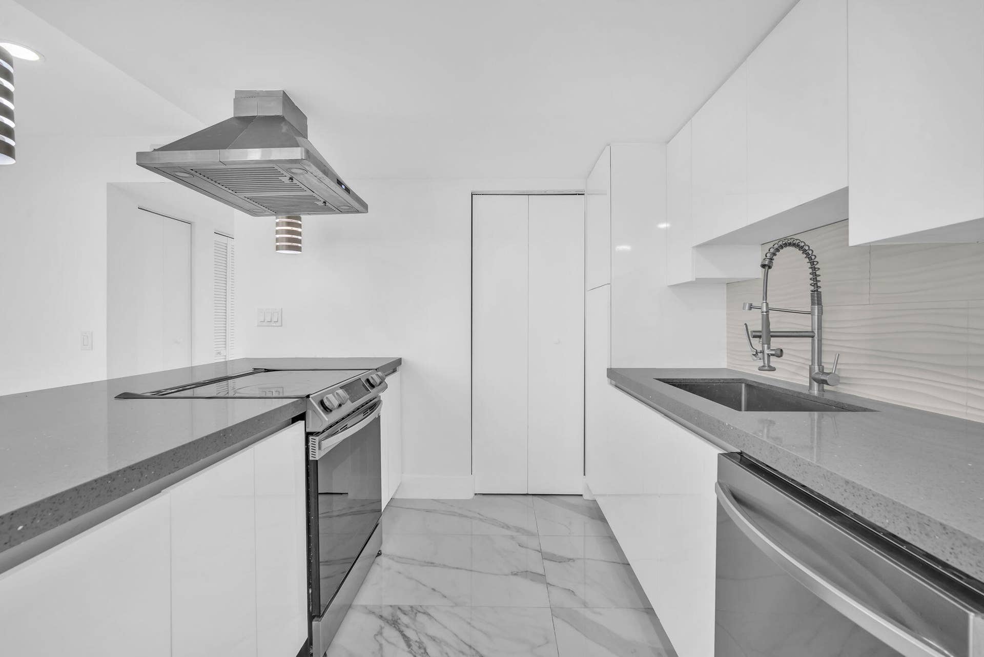 4162 SW 65th Avenue, #84, Davie, FL 33314 Contemporary kitchen featuring sleek white cabinetry, stone-finish countertops, stainless steel appliances, a professional-style range hood, and large-format tile flooring