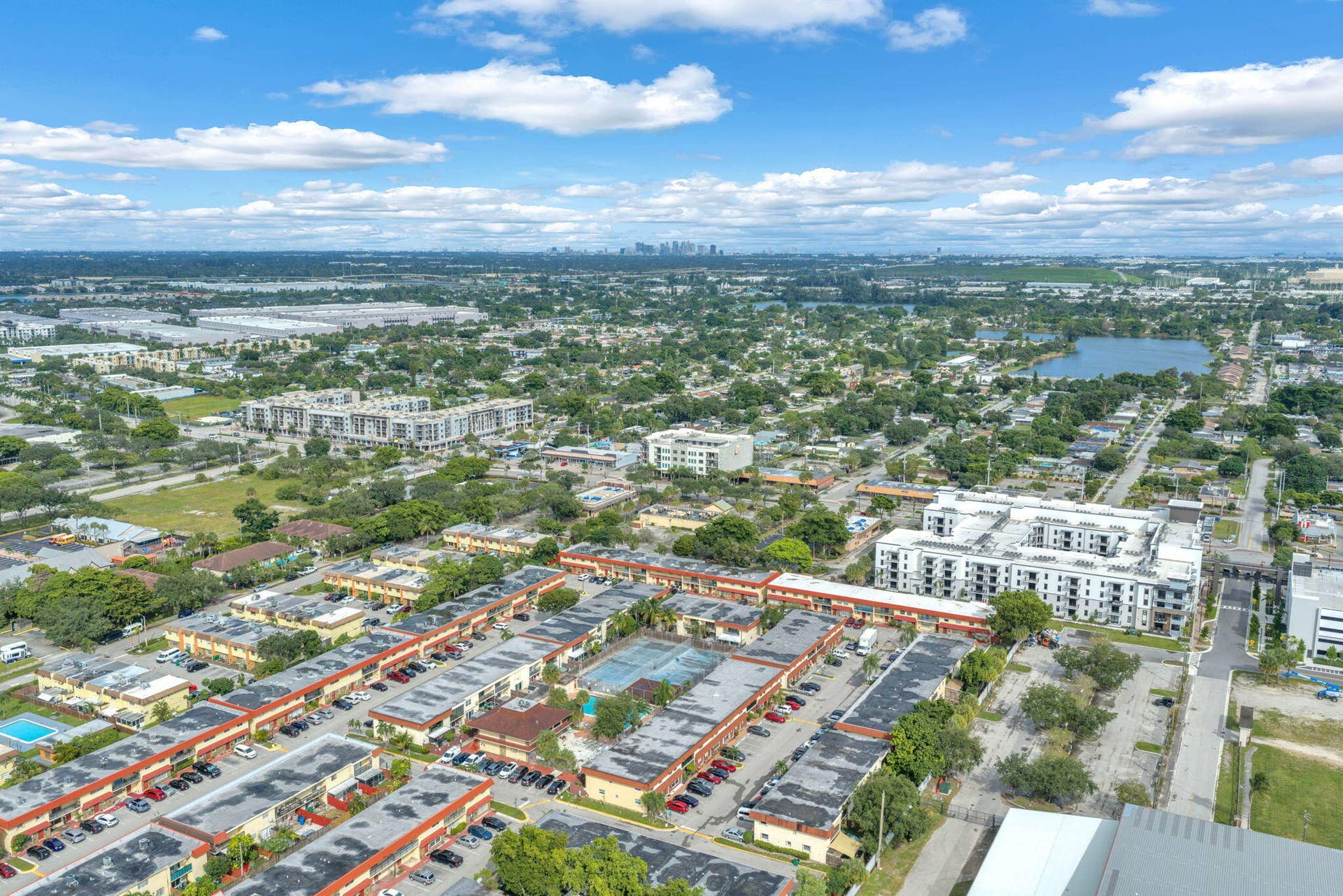 4162 SW 65th Avenue, #84, Davie, FL 33314 Aerial perspective featuring multi-unit complexes, paved parking areas, and a central tennis court within the property grounds