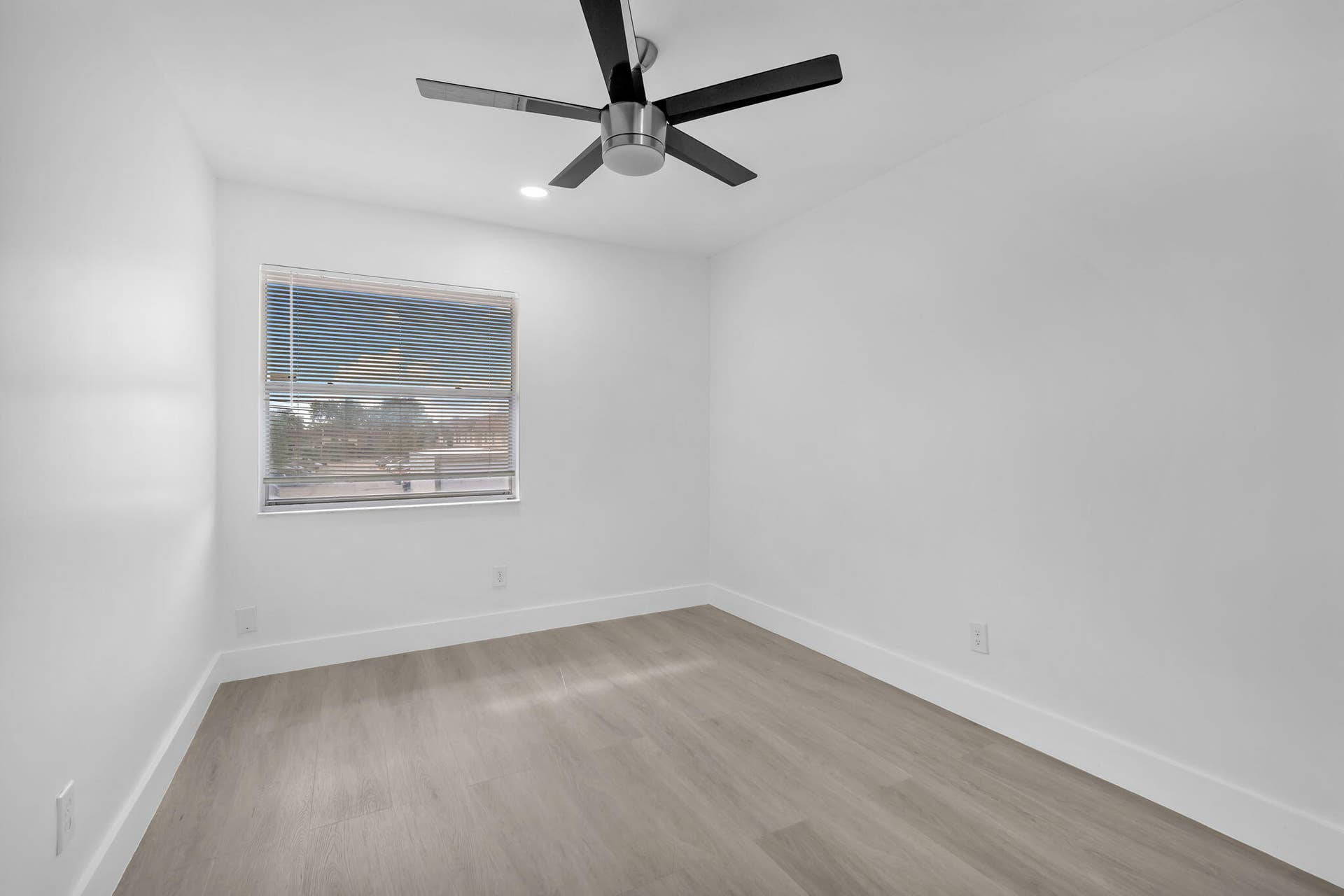 4162 SW 65th Avenue, #84, Davie, FL 33314 Neutral interior space featuring wood-finish flooring, a contemporary brushed-metal ceiling fan, and a single-hung window with installed blinds