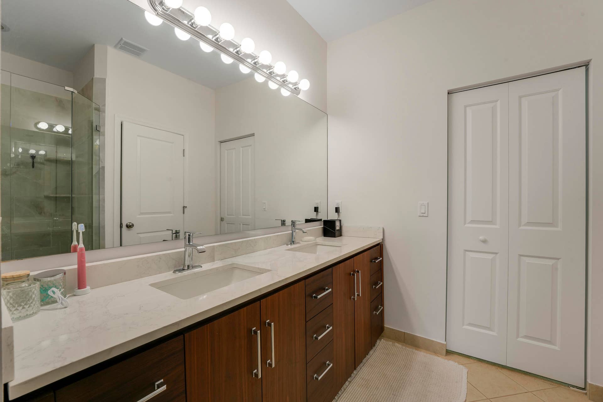 4326 Cascada Circle, Hollywood, FL 33024 Dual-sink vanity with stone-finish countertop, dark wood-finish cabinetry, full-width mirror, and glass-enclosed shower stall