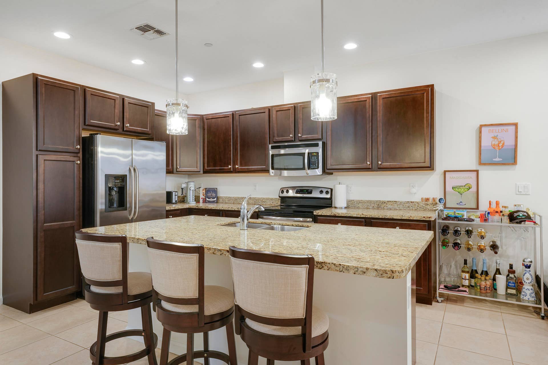 4326 Cascada Circle, Hollywood, FL 33024 Kitchen featuring dark wood cabinetry, stone countertops, stainless steel appliances, a central island with an integrated sink, and recessed ceiling lighting