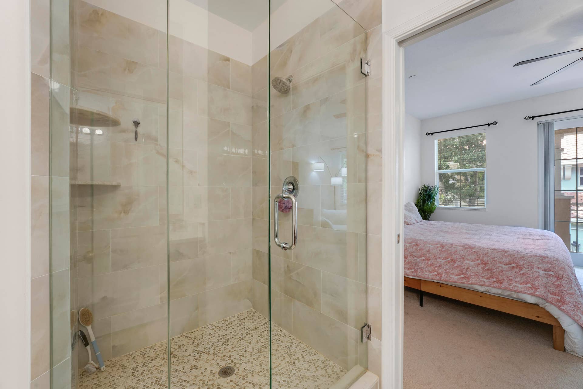 4326 Cascada Circle, Hollywood, FL 33024 Walk-in shower featuring a glass enclosure, wall-mounted shower head, built-in shelving, and stone-finish floor tiling