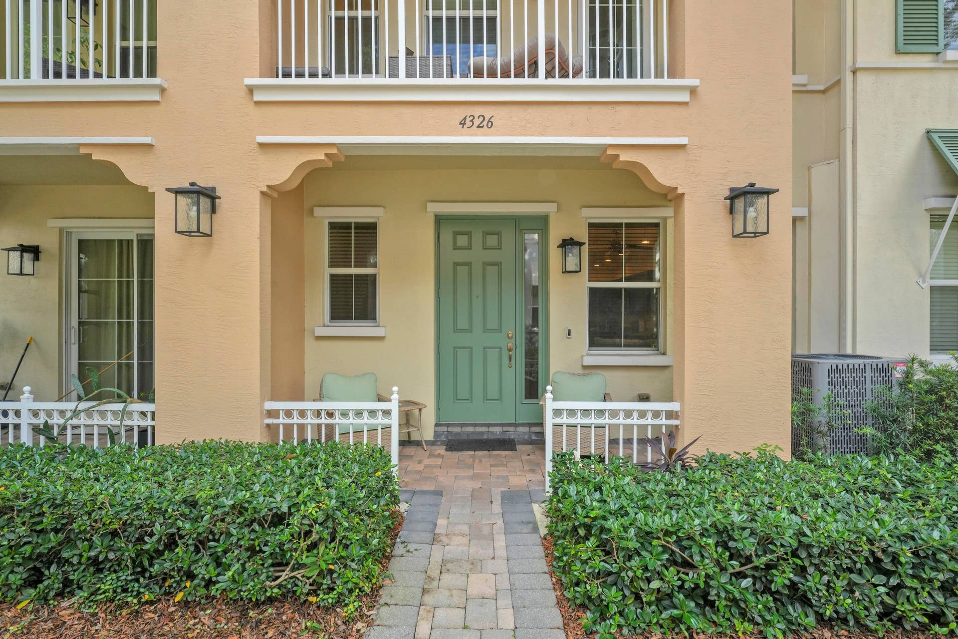 4326 Cascada Circle, Hollywood, FL 33024 Covered entryway featuring a paver walkway, green six-panel door with sidelight, decorative exterior corbels, and wall-mounted lantern fixtures