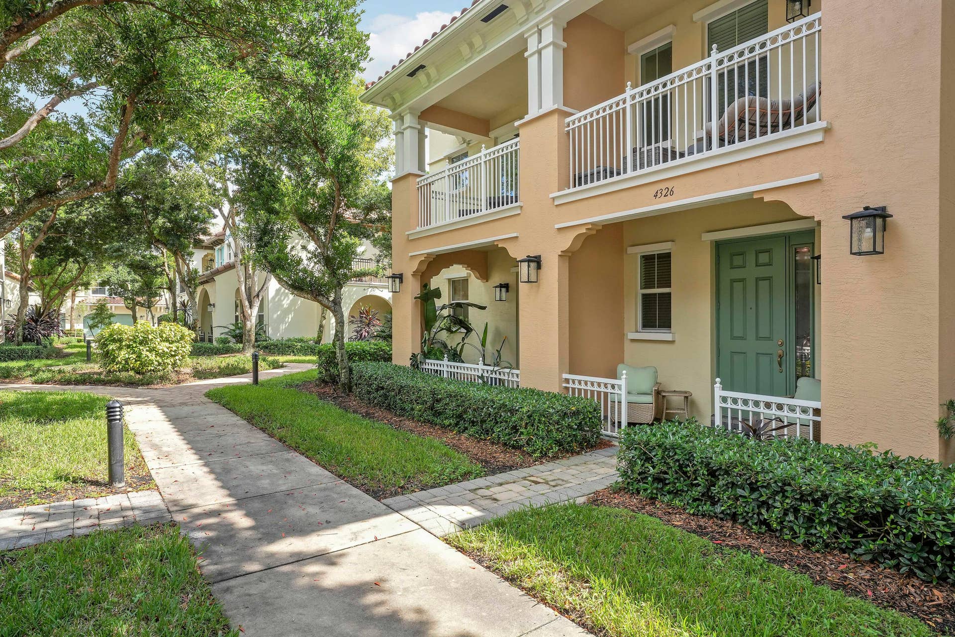 4326 Cascada Circle, Hollywood, FL 33024 Two-story exterior featuring a stucco facade, covered balconies with white railings, a front porch, and manicured landscaping