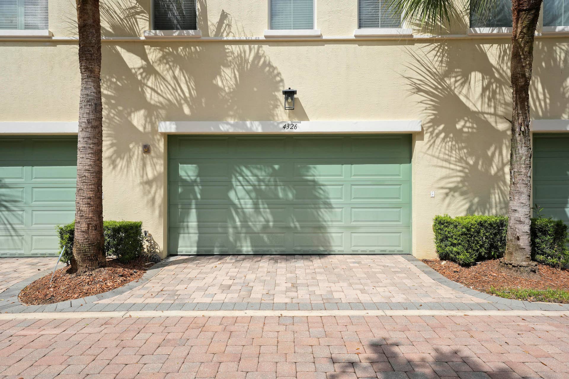 4326 Cascada Circle, Hollywood, FL 33024 Stucco exterior featuring a multi-panel garage door, decorative exterior wall sconce, and paver stone driveway