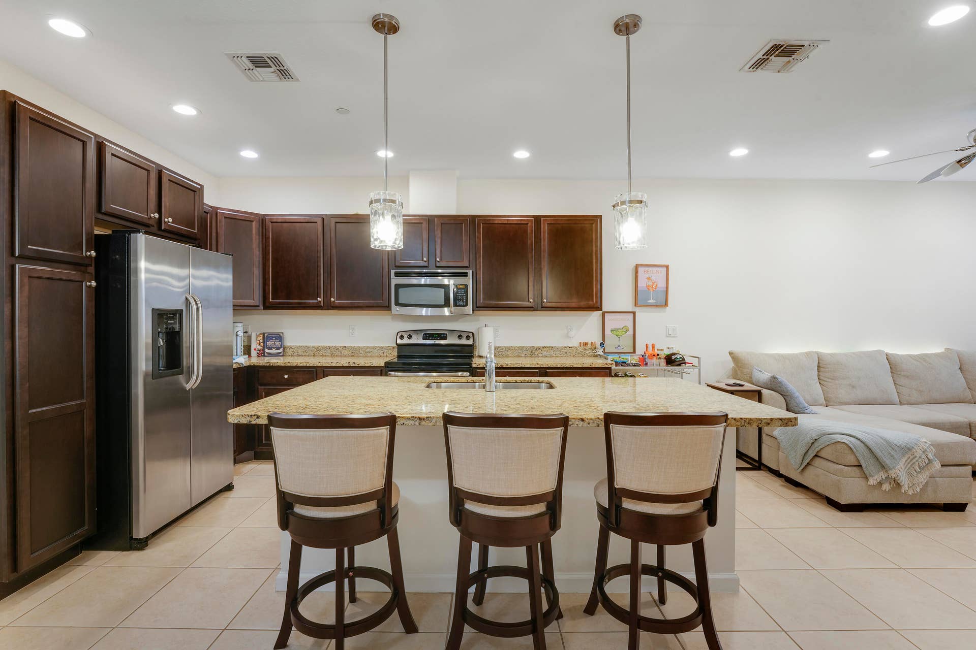 4326 Cascada Circle, Hollywood, FL 33024 Kitchen featuring dark wood-finish cabinetry, stone countertops, central island with integrated sink, stainless steel appliances, and recessed lighting