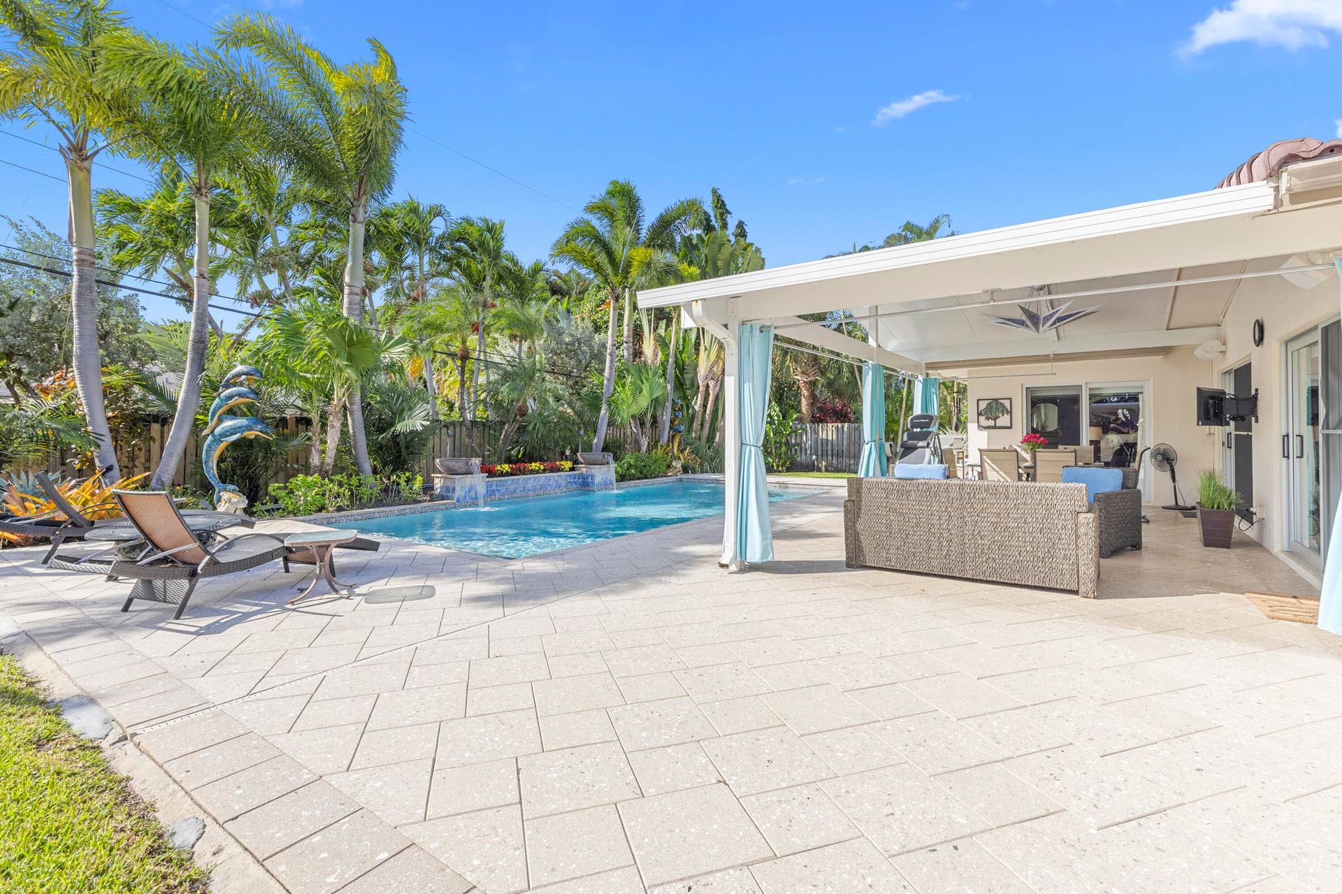 2317 NW 6th Avenue, Wilton Manors, FL 33311 Covered patio with paver flooring, swimming pool featuring a decorative water feature, and mature palm trees