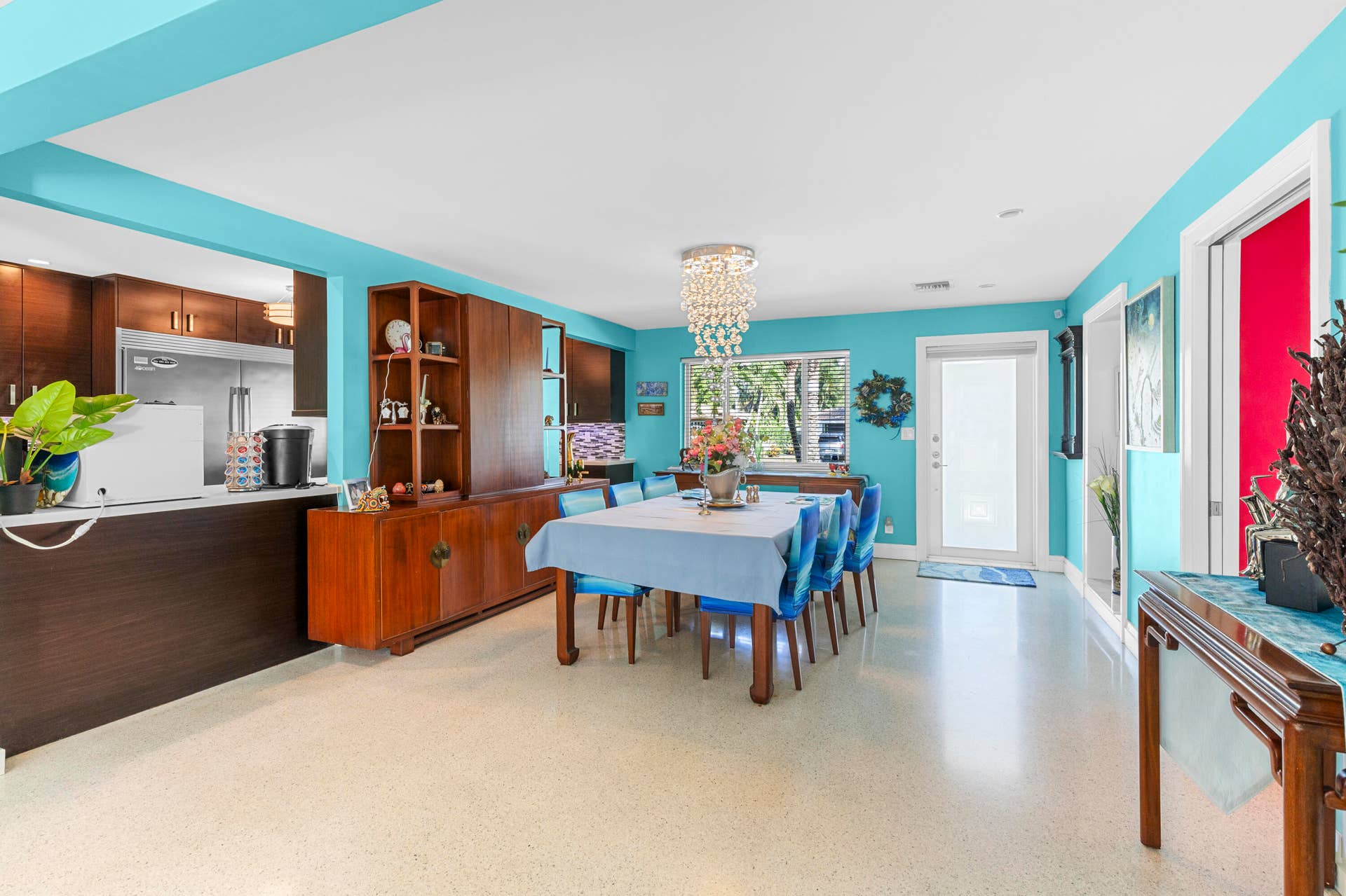 2317 NW 6th Avenue, Wilton Manors, FL 33311 Open-concept dining area featuring terrazzo flooring, built-in mahogany cabinetry, a crystal chandelier, and large window