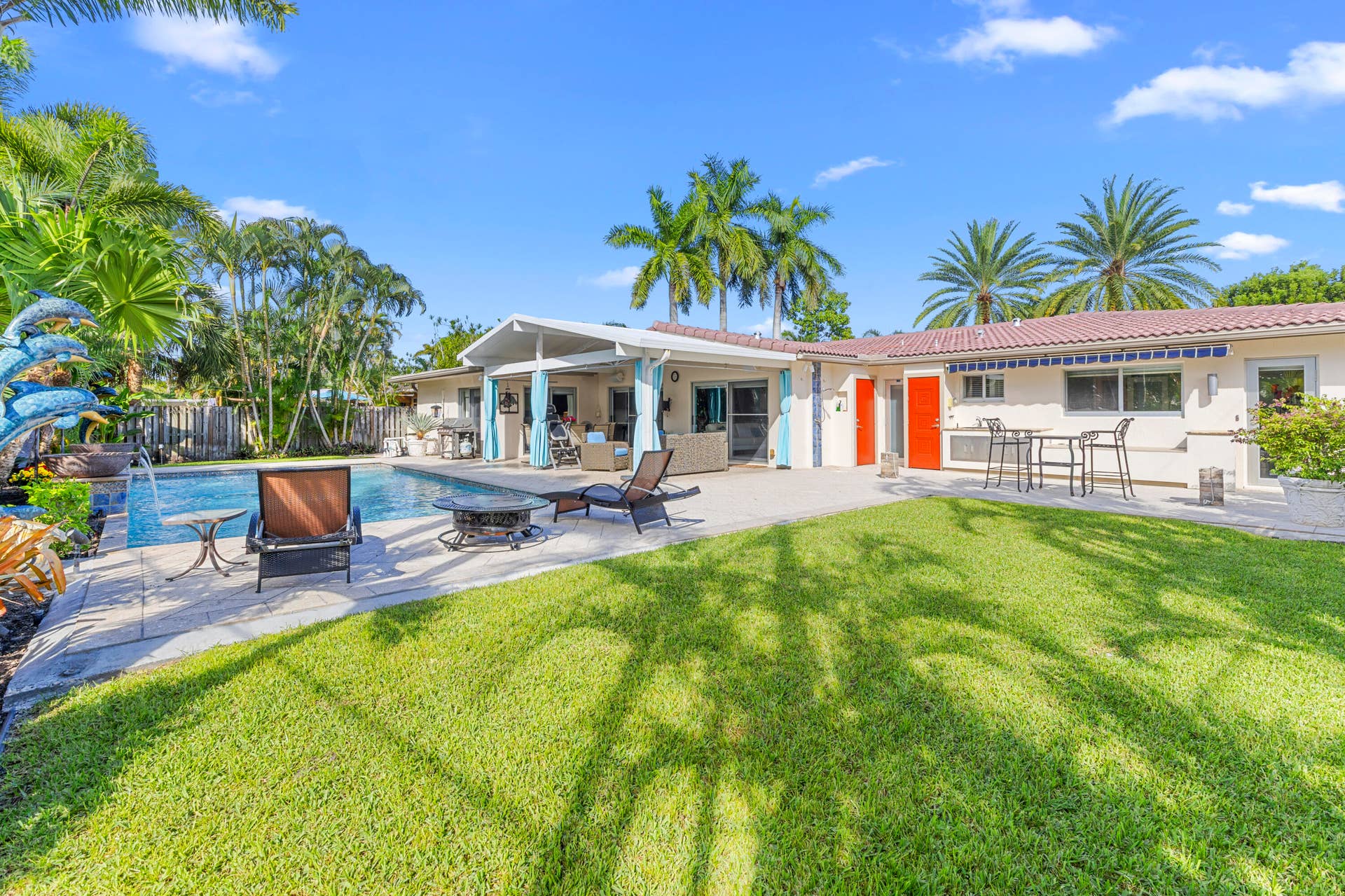 2317 NW 6th Avenue, Wilton Manors, FL 33311 Backyard featuring a concrete pool deck, in-ground swimming pool, covered patio, manicured lawn, and mature palm trees