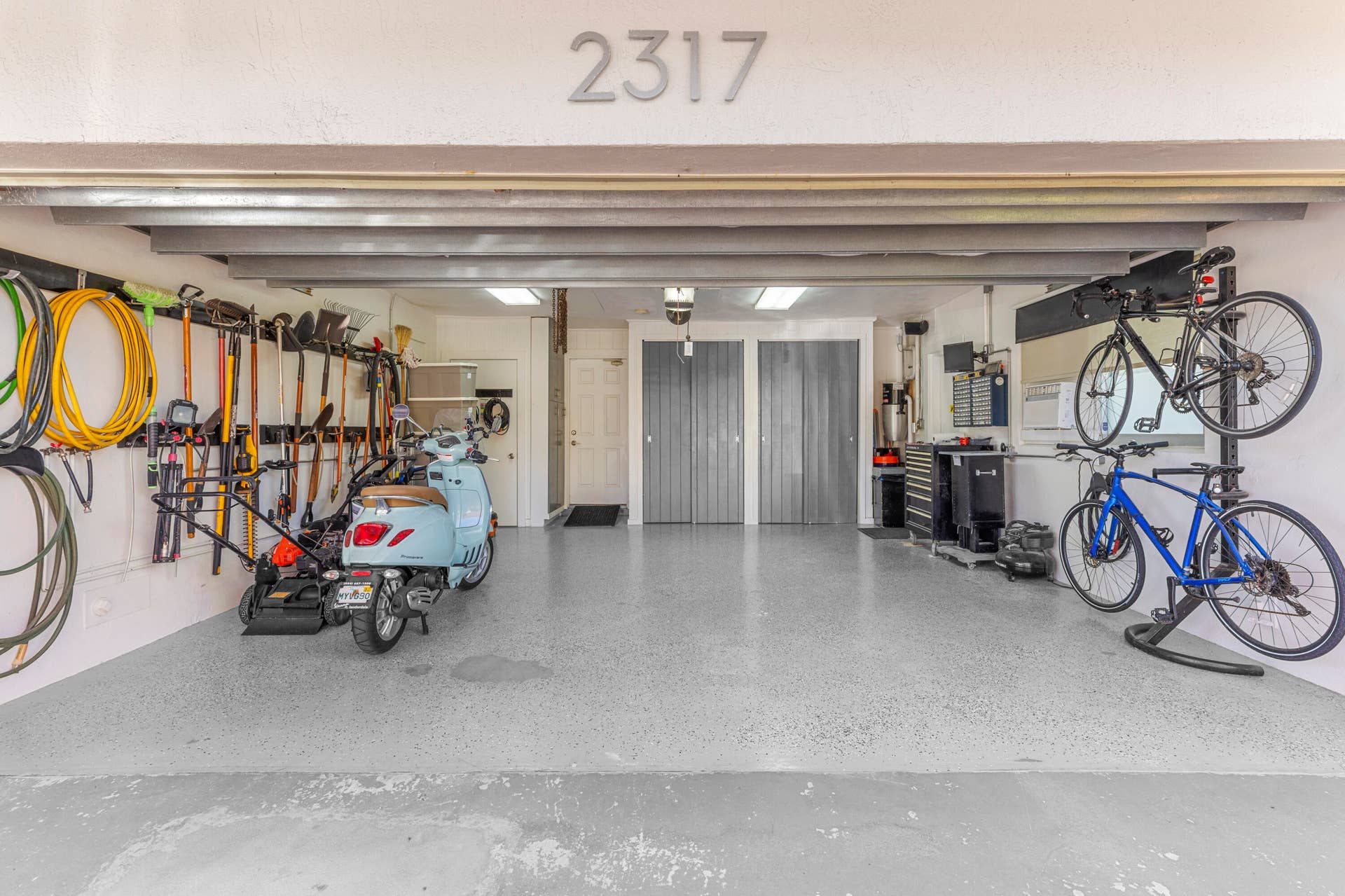 2317 NW 6th Avenue, Wilton Manors, FL 33311 Attached two-car garage featuring epoxy-coated flooring, overhead fluorescent lighting, built-in wall-mounted organizational tracks, and dual floor-to-ceiling storage closets