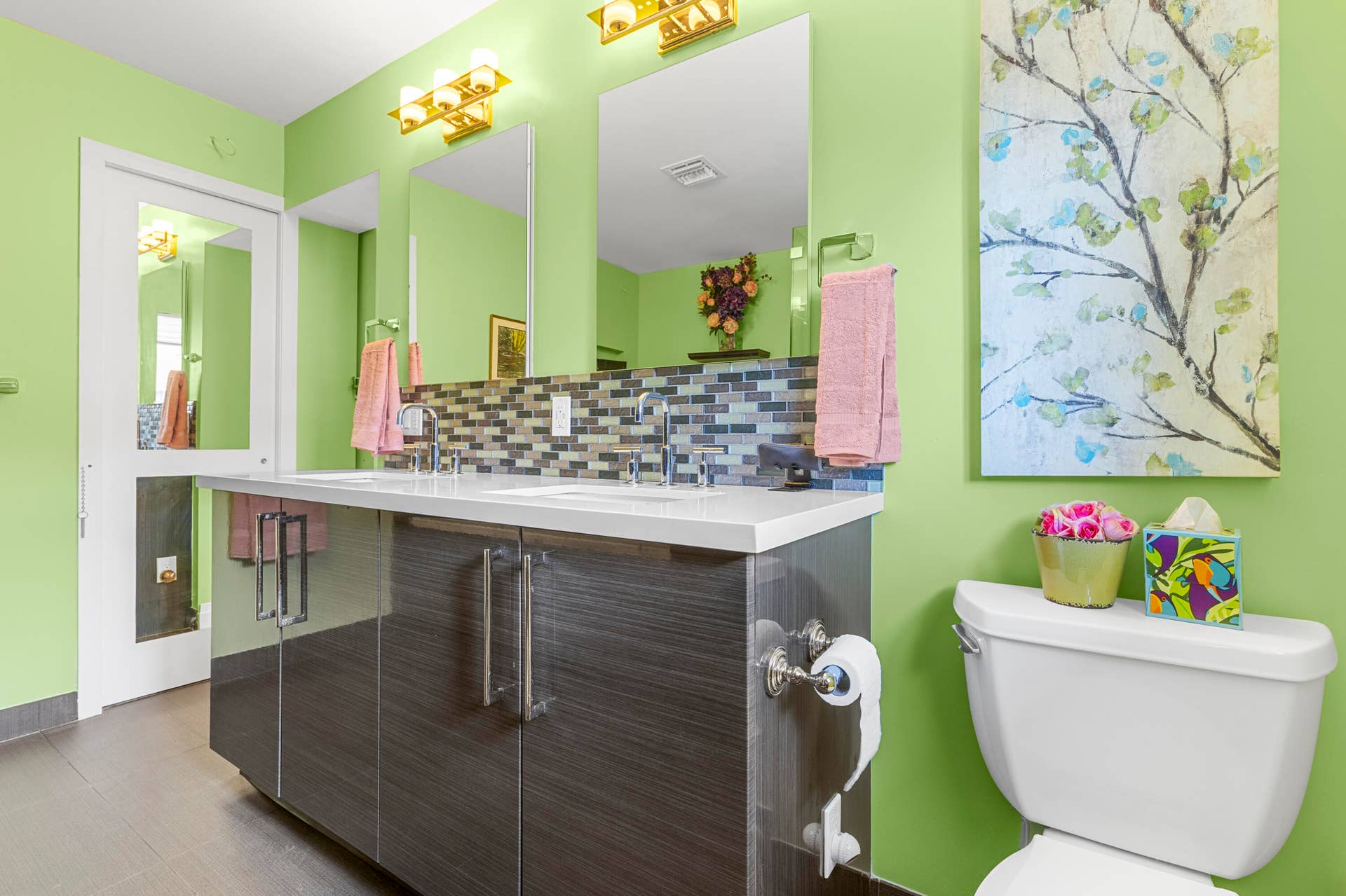2317 NW 6th Avenue, Wilton Manors, FL 33311 Dual-sink vanity featuring a solid surface countertop, high-gloss cabinetry, linear tile backsplash, and wall-mounted lighting