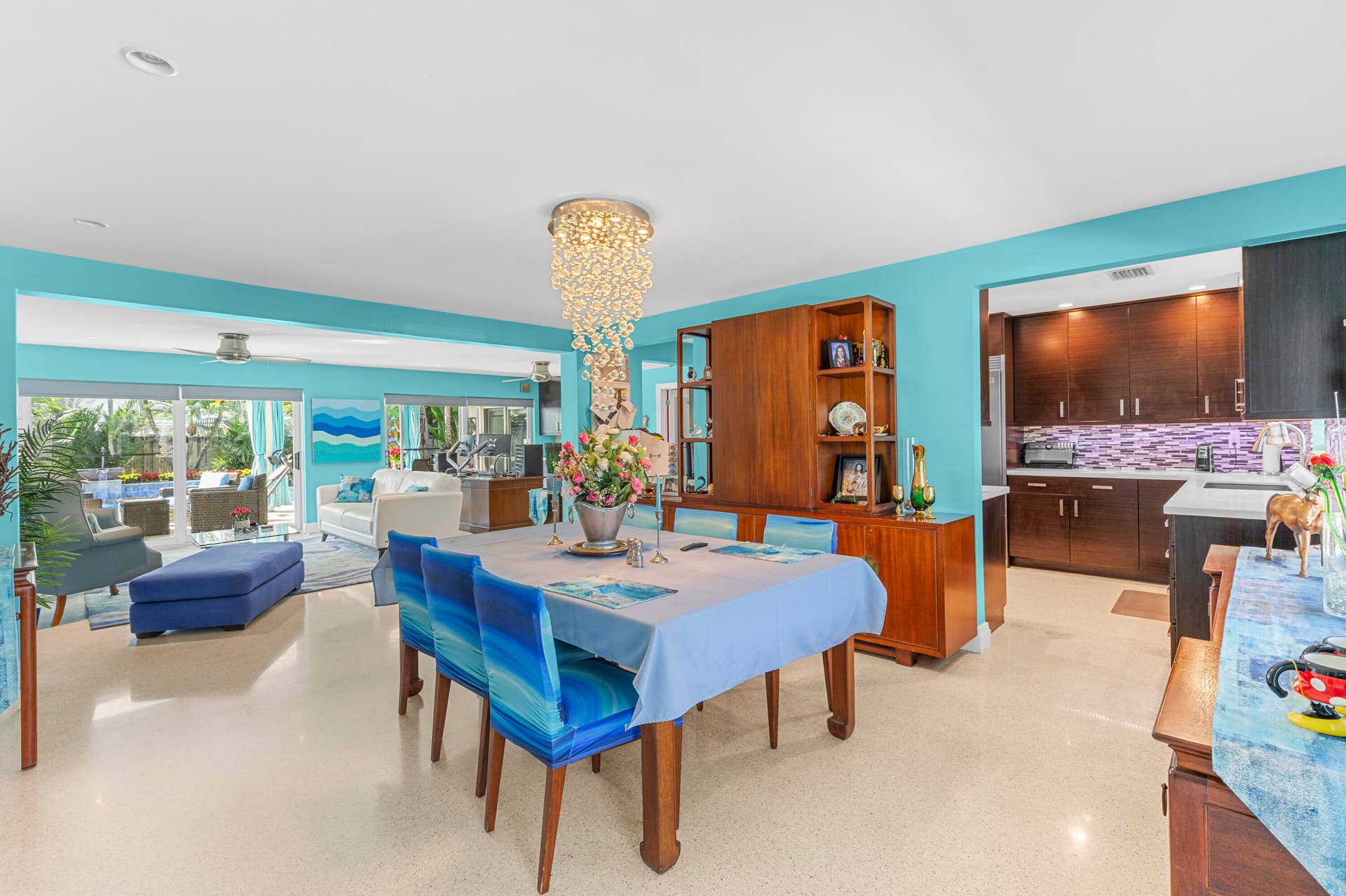 2317 NW 6th Avenue, Wilton Manors, FL 33311 Open-concept interior featuring light-reflecting terrazzo flooring, custom built-in wood cabinetry, recessed lighting, and a tiered crystal chandelier