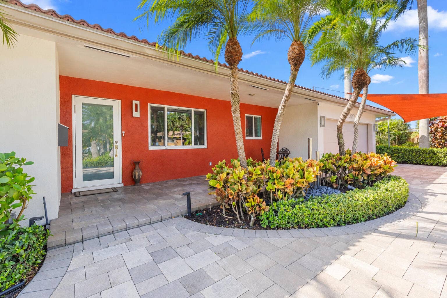 2317 NW 6th Avenue, Wilton Manors, FL 33311 Stucco exterior with contrasting masonry finishes, paved hardscaping, landscaped garden beds, and palm trees