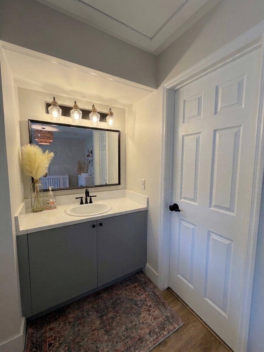 2941 NE 185TH Street, #1303, Aventura, FL 33180 Vanity featuring a solid-surface countertop with an integrated oval sink, matte black hardware, four-light wall fixture, and framed mirror
