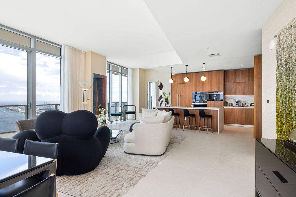 Floor-to-ceiling windows, custom wood-finish cabinetry, built-in panel-ready appliances, stone-topped kitchen island, and large-format tile flooring