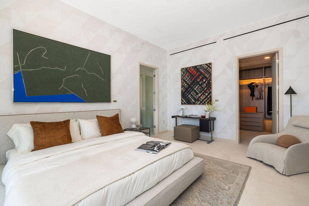 Bedroom featuring textured wall covering, recessed ceiling track lighting, and a walk-in closet with built-in cabinetry