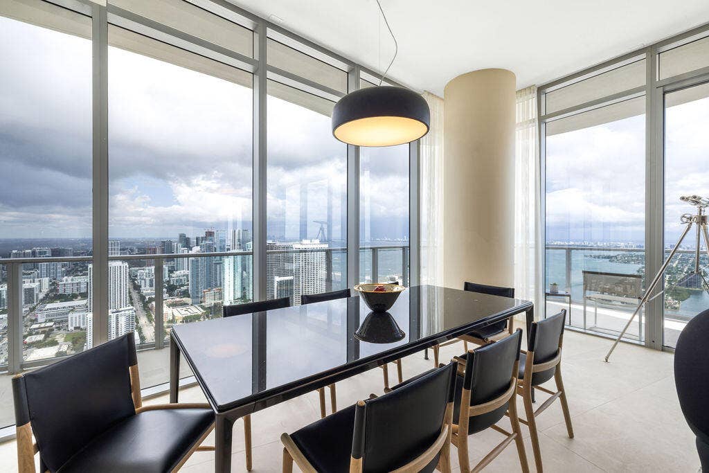 Floor-to-ceiling glass walls, sleek tile flooring, structural cylindrical column, and dome pendant lighting