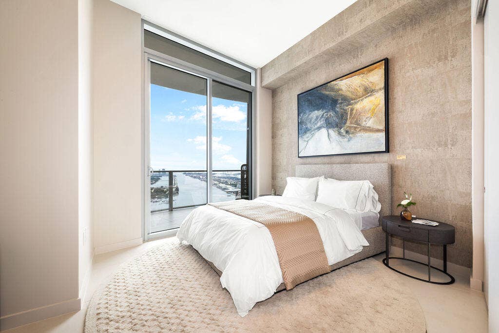 Floor-to-ceiling glass sliding door, large private balcony, textured stone feature wall, and neutral polished flooring