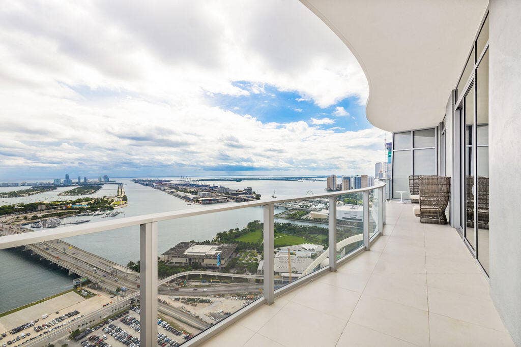 Curved wrap-around balcony featuring expansive tile flooring and a glass panel railing