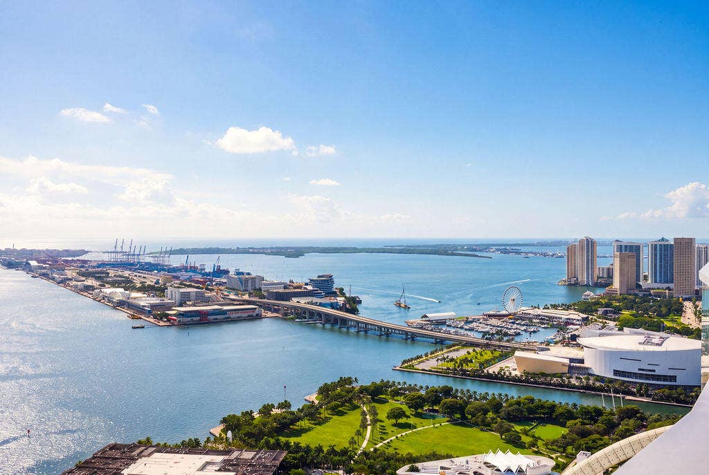 High-altitude perspective featuring expansive water, cityscape, harbor, and parkland surroundings