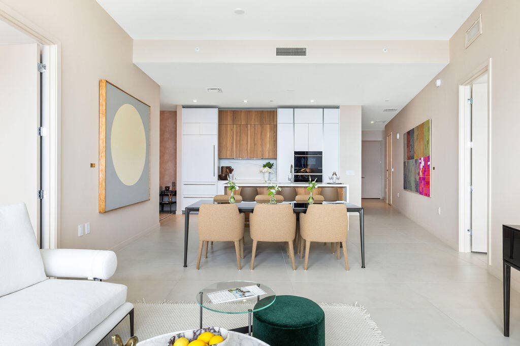 Open-concept kitchen featuring custom wood-finish and matte white cabinetry, integrated appliances, and a central island with a stone-finish countertop