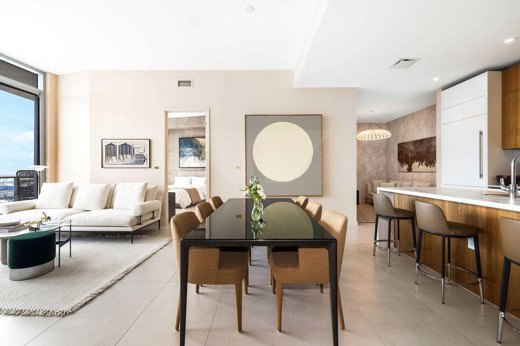 Open-concept interior featuring large-format tile flooring, floor-to-ceiling windows, and a kitchen island with wood-veneer cabinetry and a solid-surface countertop
