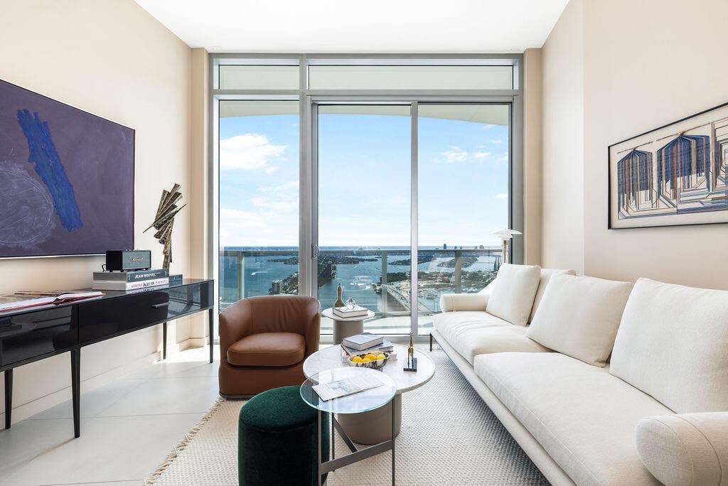 Floor-to-ceiling windows with sliding door access to a balcony, complemented by neutral tile flooring