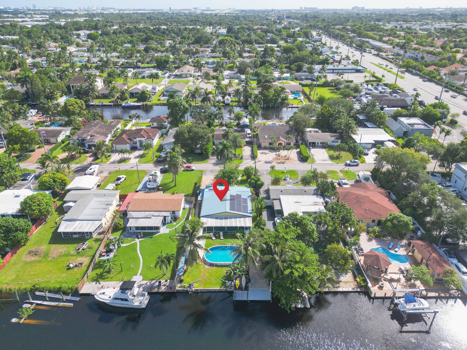 Waterfront property featuring a private swimming pool, solar panel array, lawn area, and a dedicated boat dock