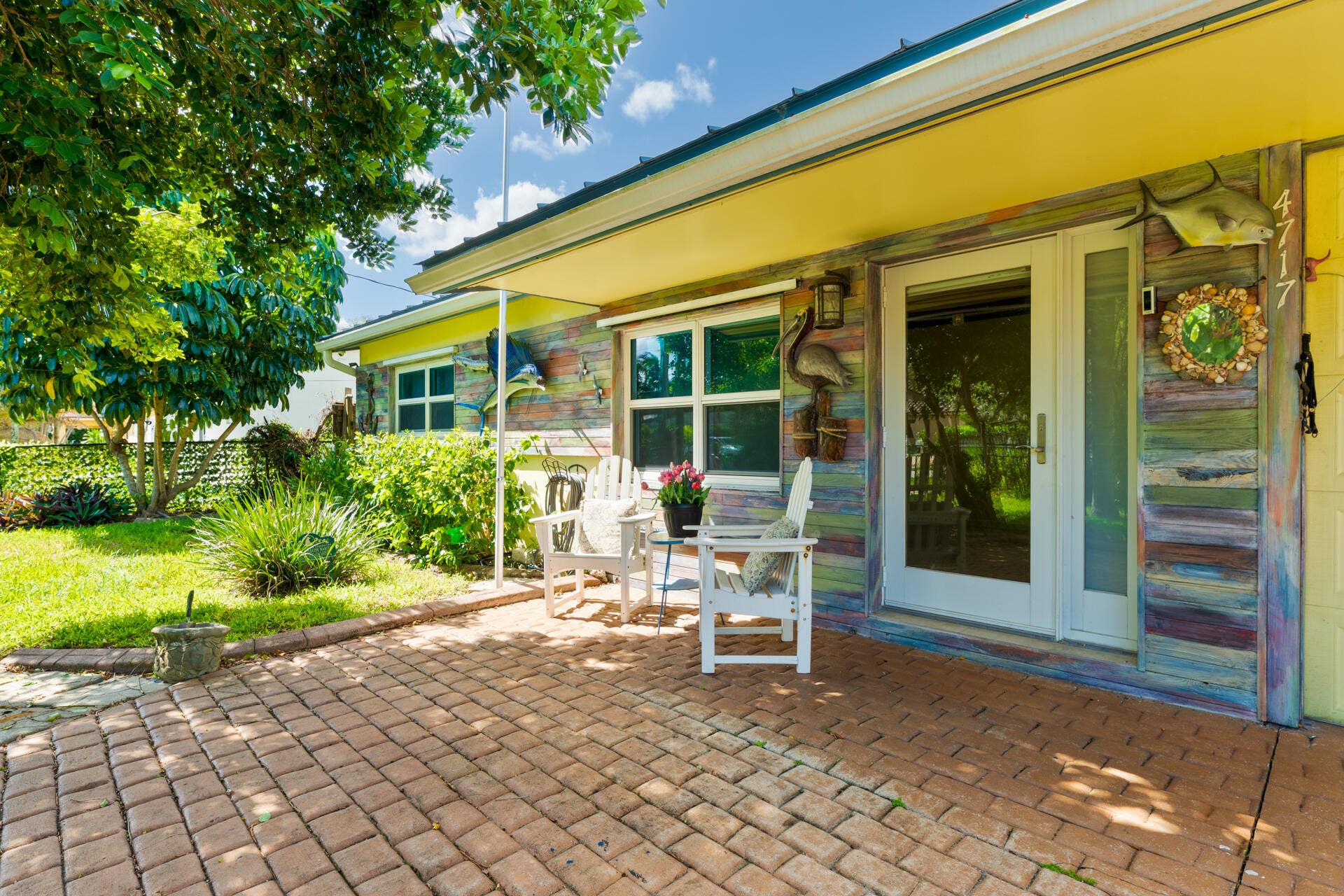 Exterior facade featuring multi-tone horizontal siding, brick paver patio, covered entryway, and large windows with integrated glass sidelights