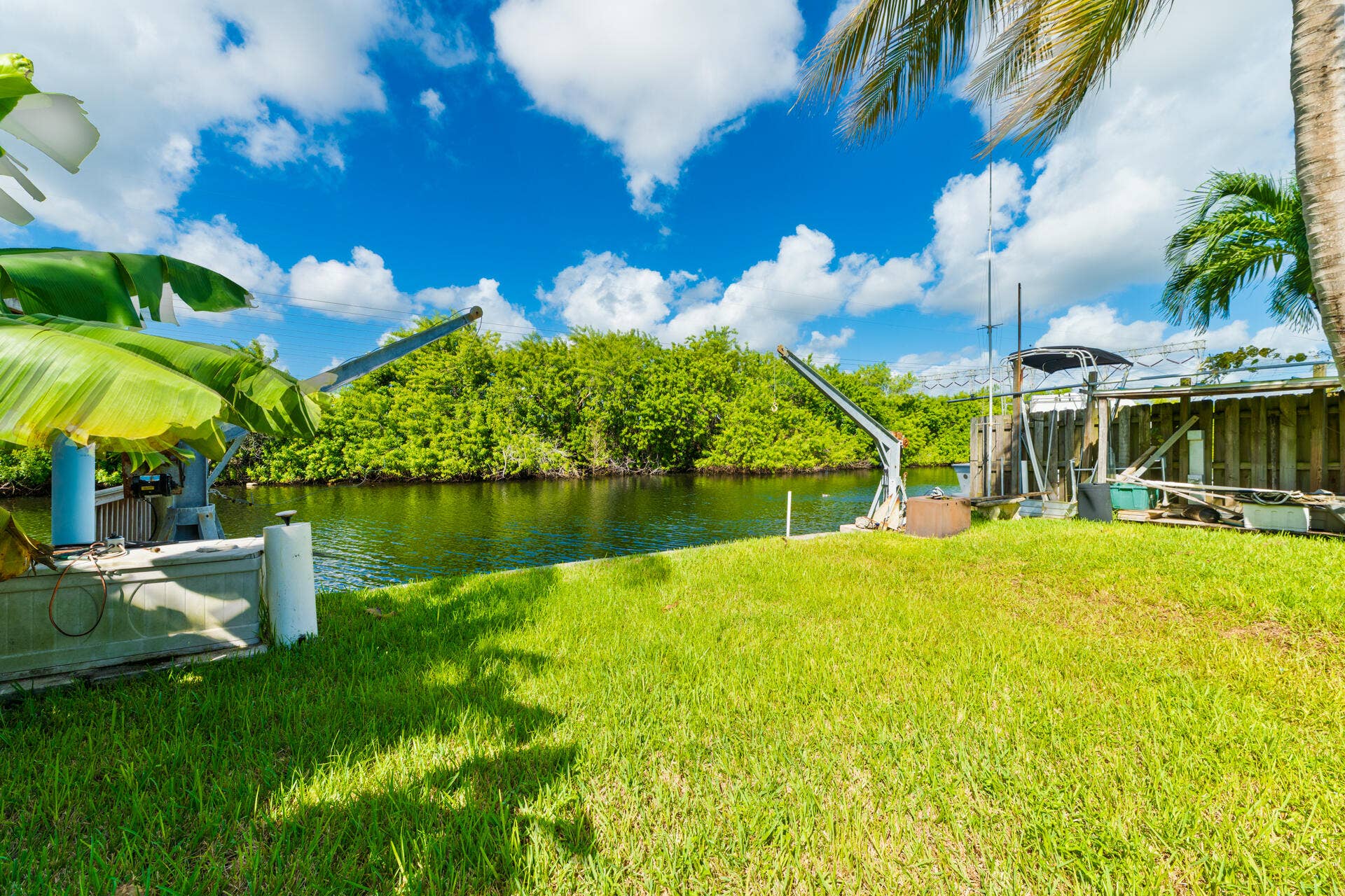 Waterfront parcel featuring a manicured lawn, boat davits, and direct canal access