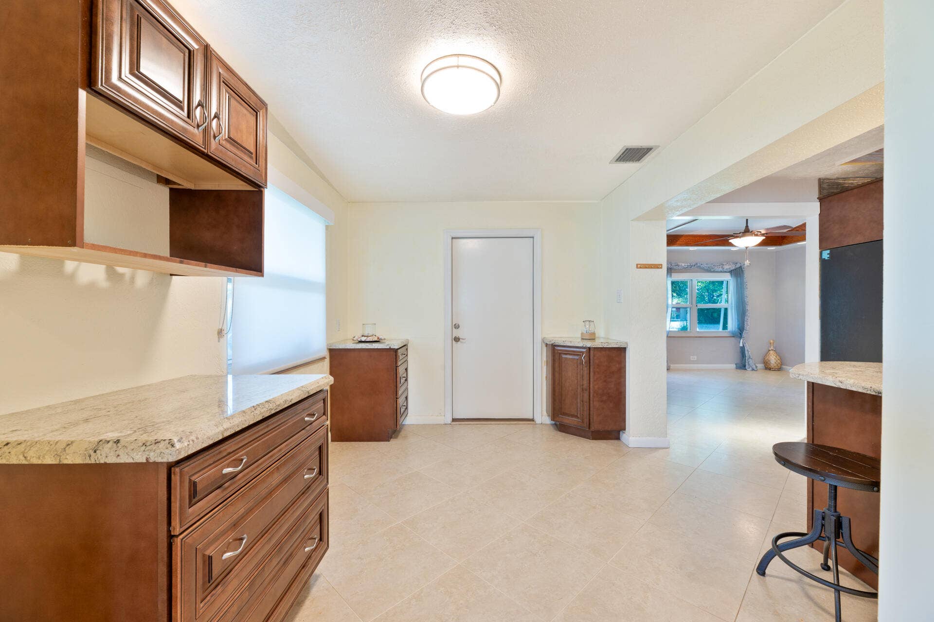 Dining area featuring wood cabinetry, stone-finish countertops, tile flooring, and a flush-mount ceiling light fixture