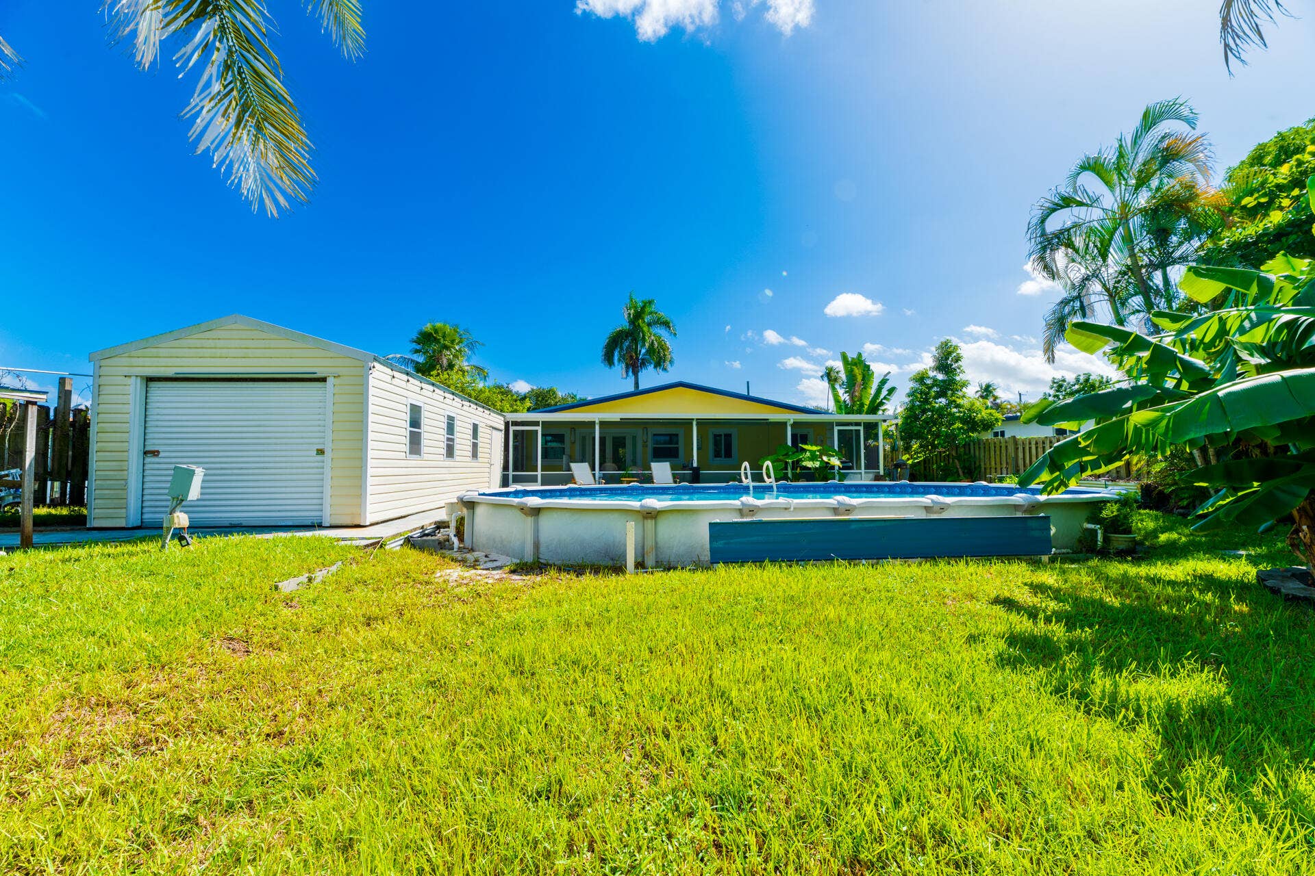 Backyard featuring a 33' above-ground swimming pool, detached garage, screened-in porch, and mature landscaping