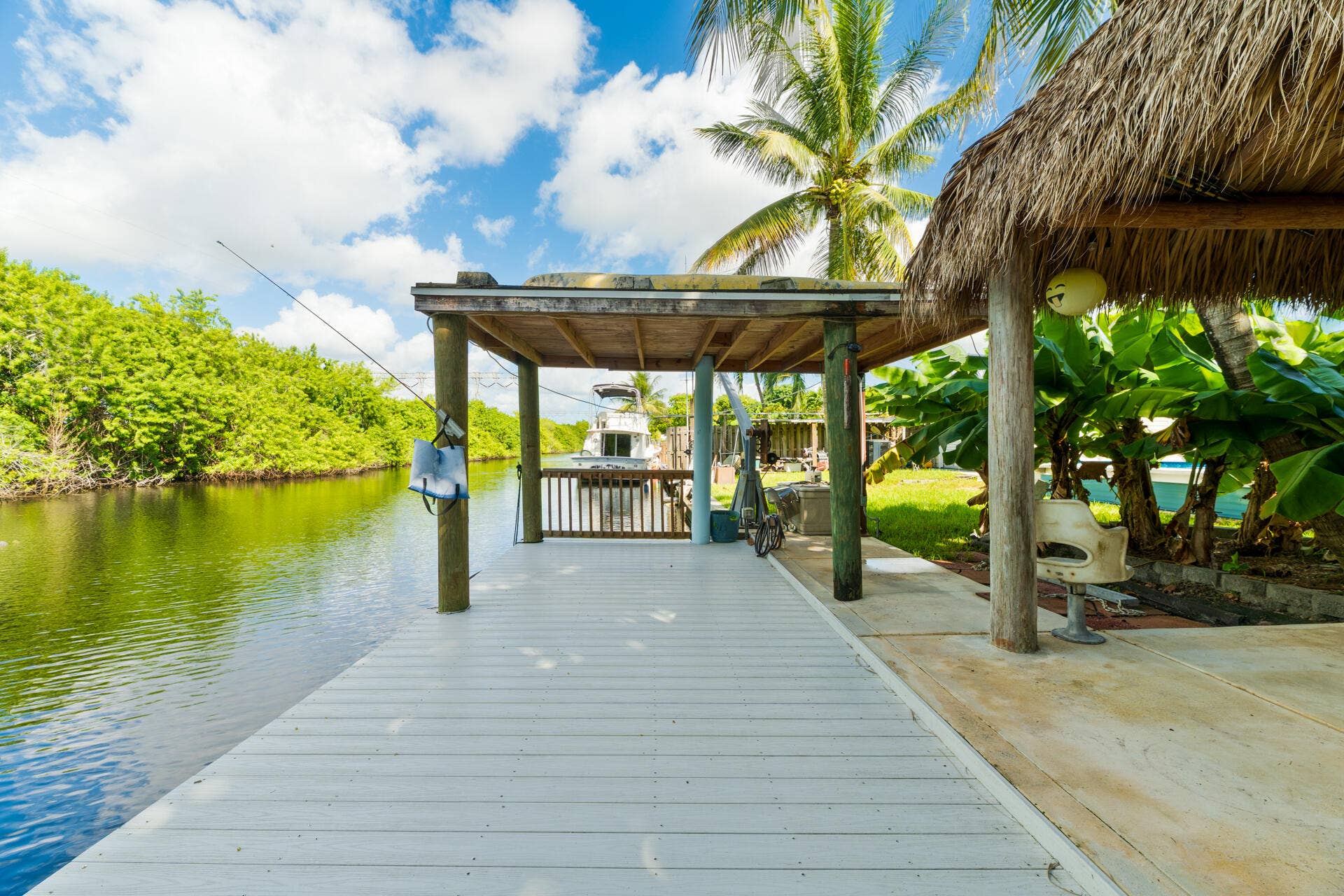 Waterfront dock featuring a covered area, thatched-roof structure, and carefree composite decking