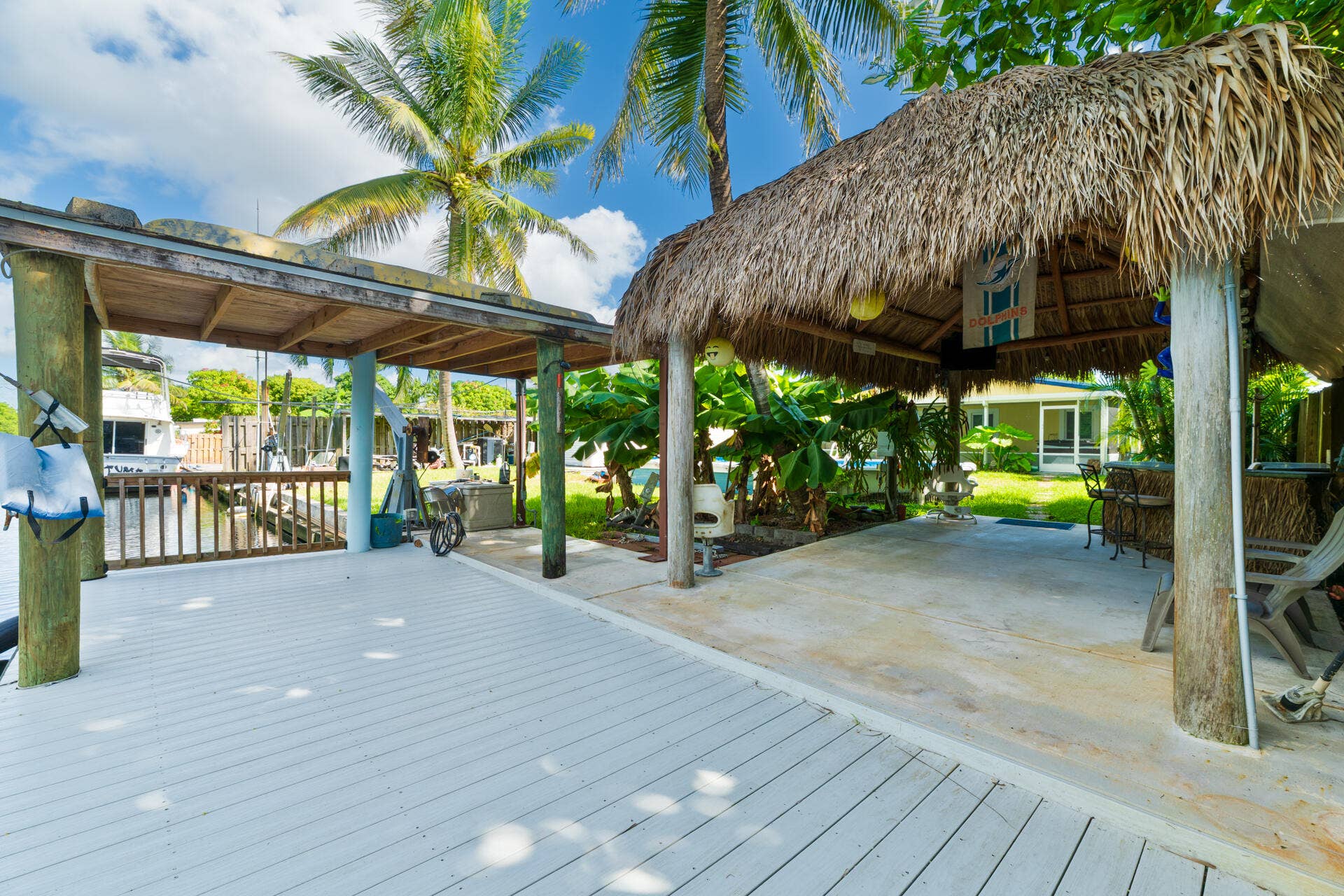 Waterfront dock featuring composite decking, a thatched-tiki